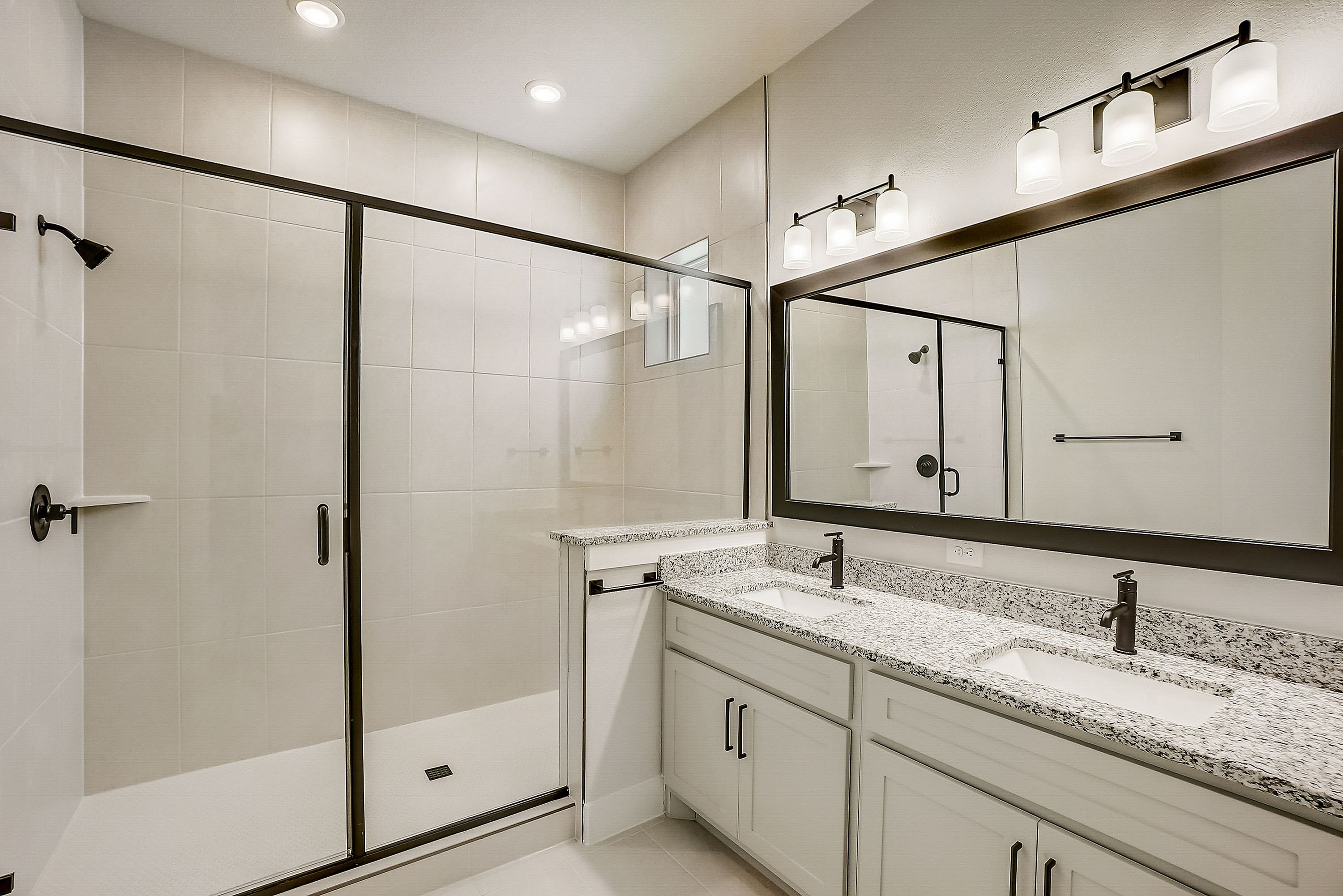 dual vanity area in primary bathroom with spacious walk in shower