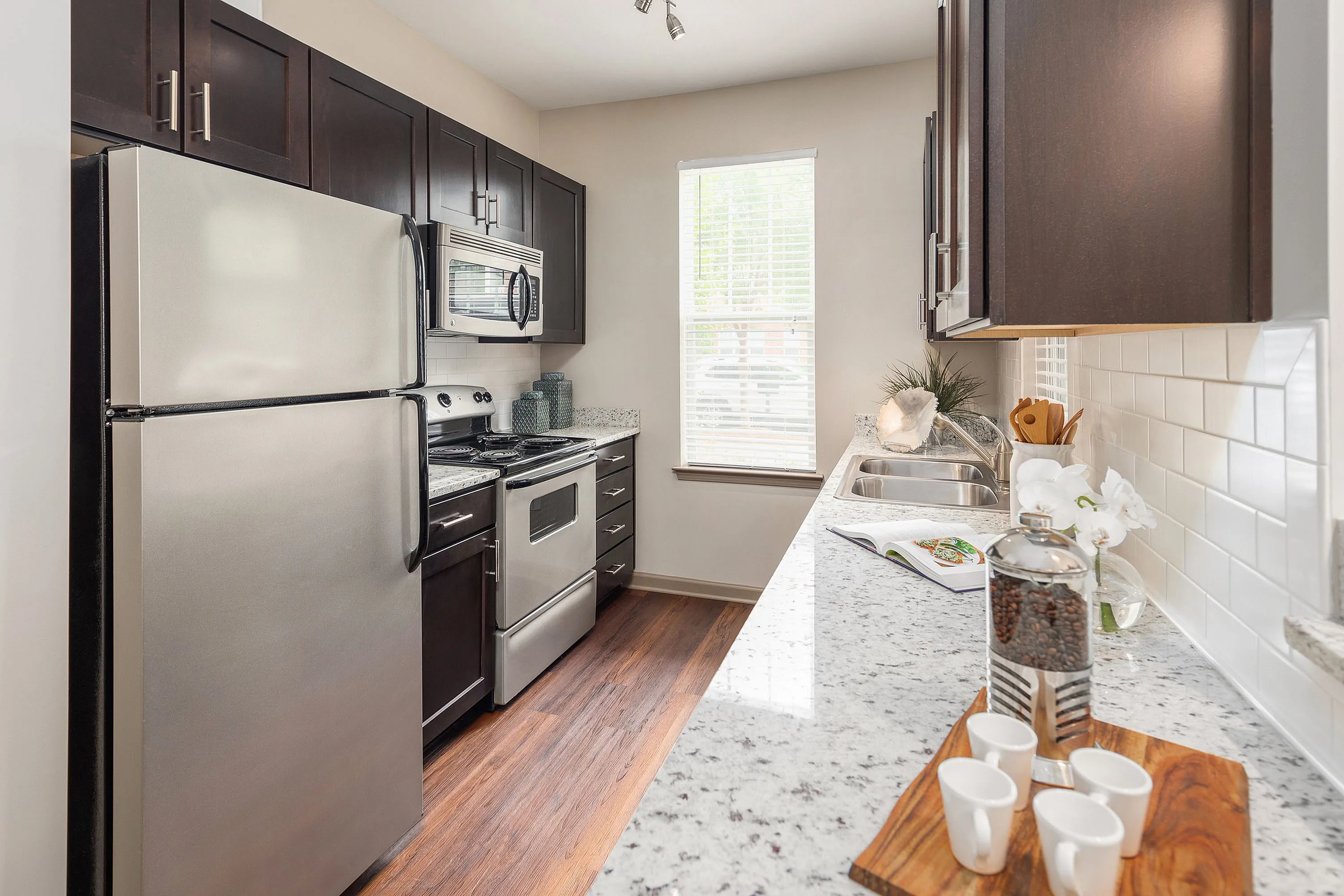 Sleek modern kitchen with stainless steel appliances, granite countertops, and dark wood cabinets.