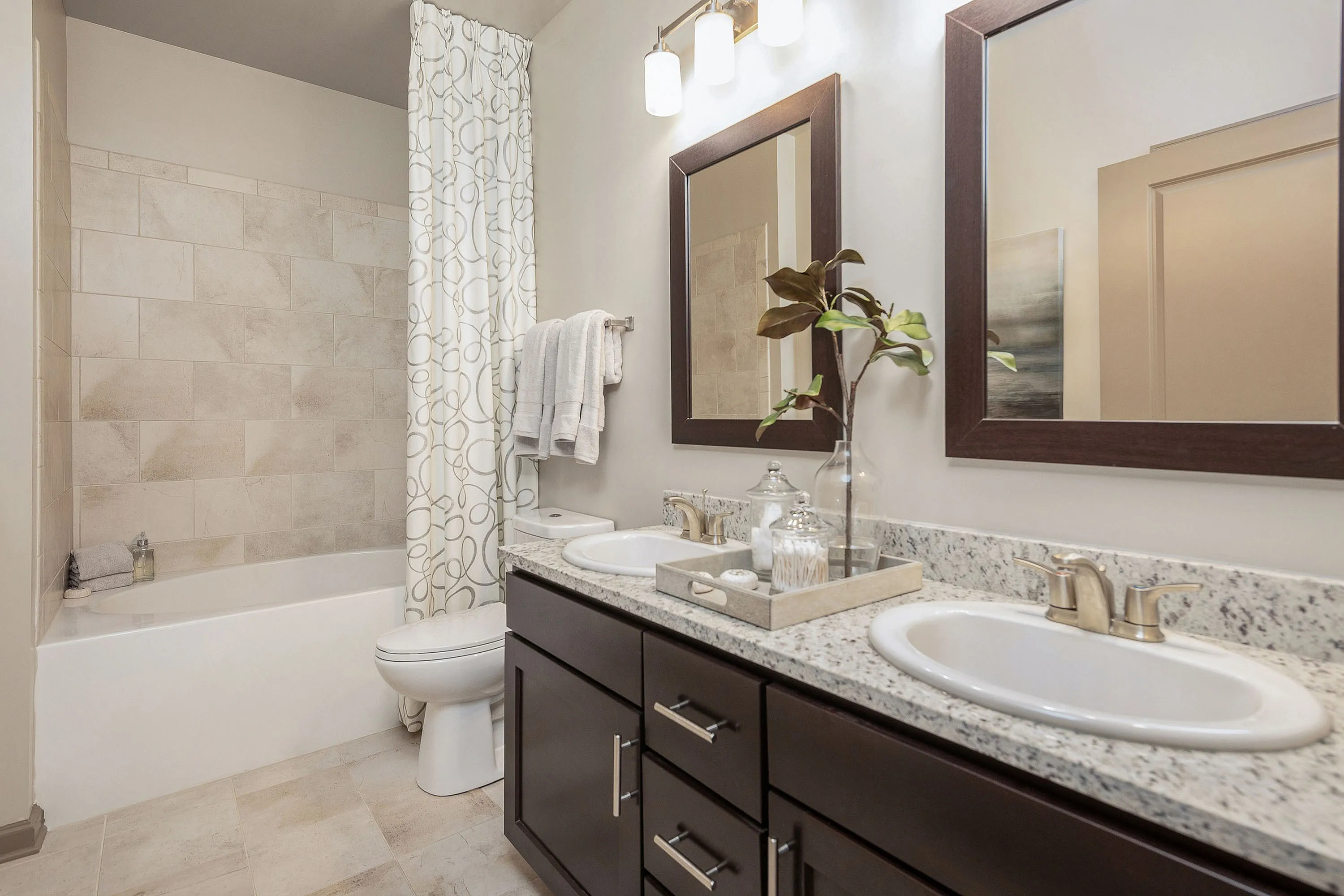Luxurious bathroom featuring modern countertops, dual sinks, and a stylish bath area.