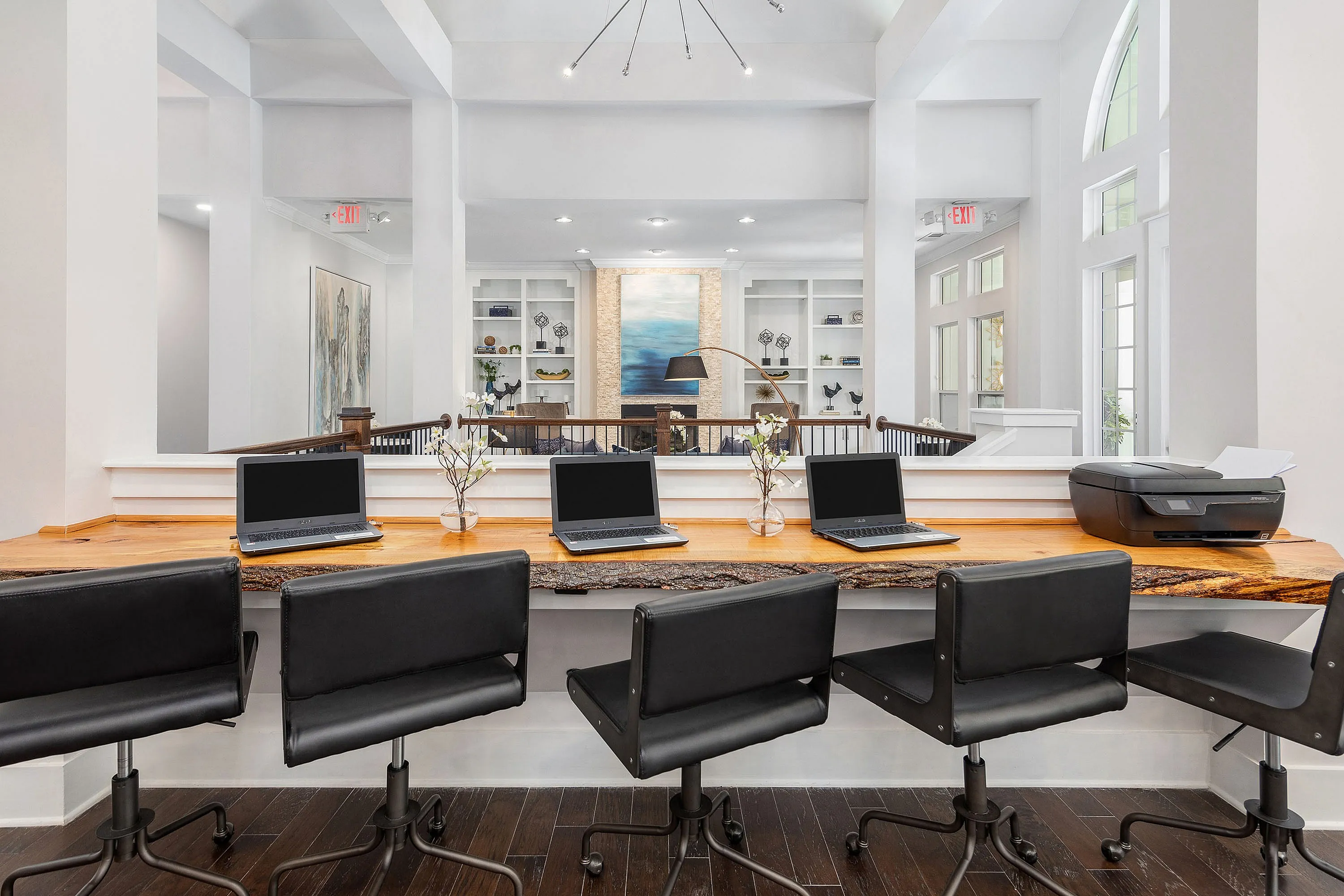 Sophisticated co-working area with a natural wood counter, laptops, and elegant decor.