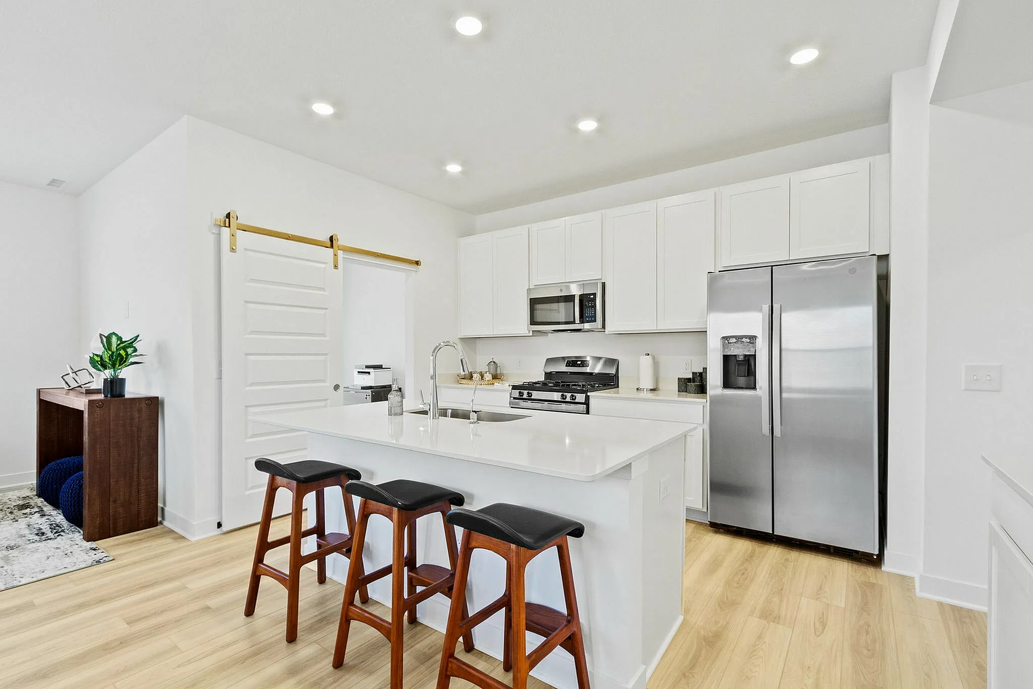 Brownsburg, IN, Townhomes with In-Unit Washer and Dryer - Wynne Farms - Kitchen With White Cabinets, Stainless Steel Appliances, A Large Island, and Wood Style Flooring.