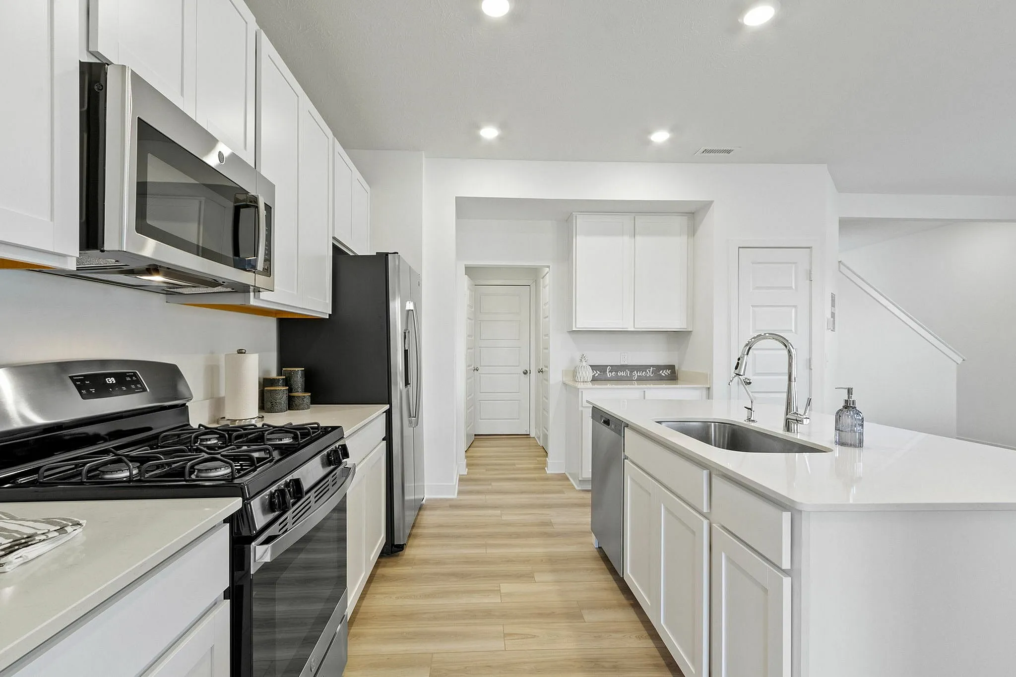 Upscale kitchen with white cabinets barn door and stainless steel appliances