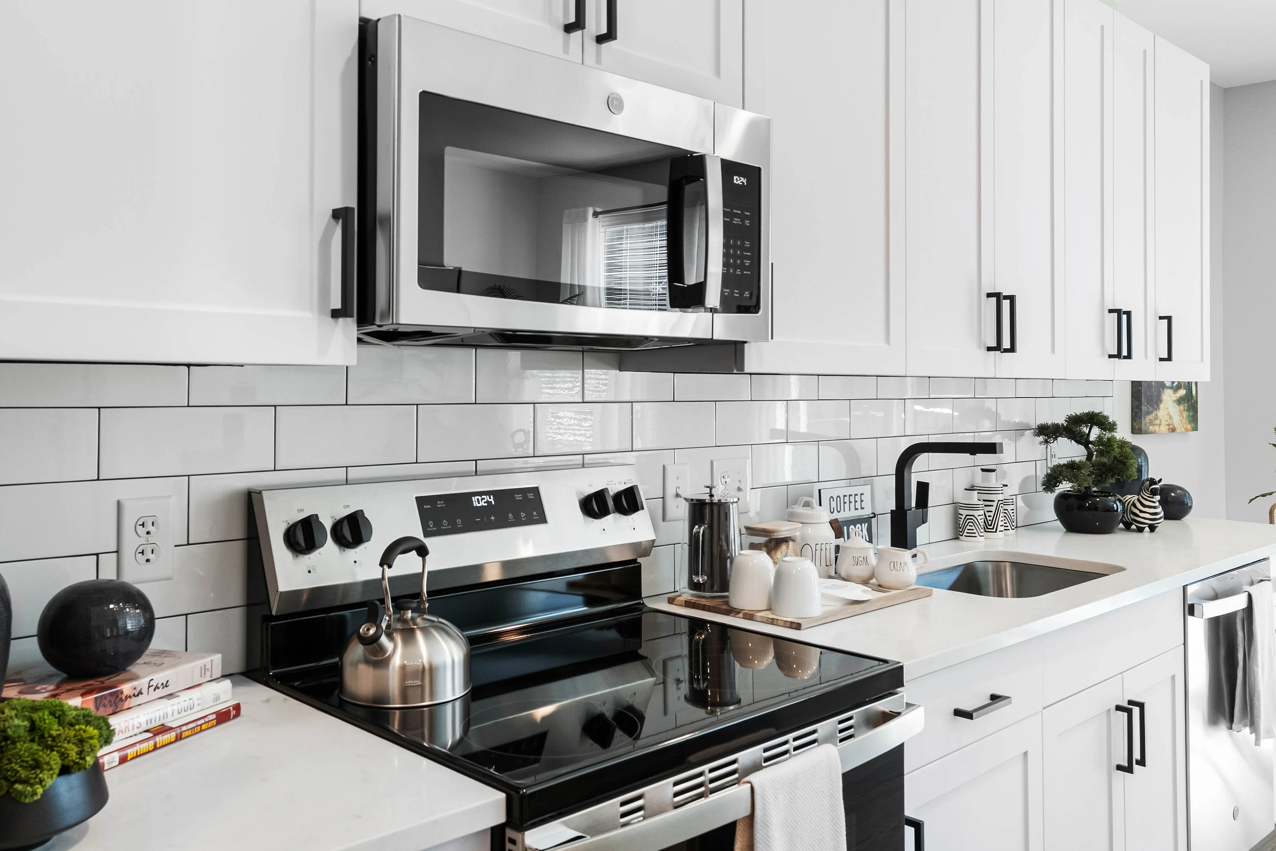 Luxury Apartments in Richmond, VA - The James at Springline - A Kitchen with White Cabinetry, Stainless Steel Appliances, Quartz Countertops, and a Subway Tile Backsplash.
