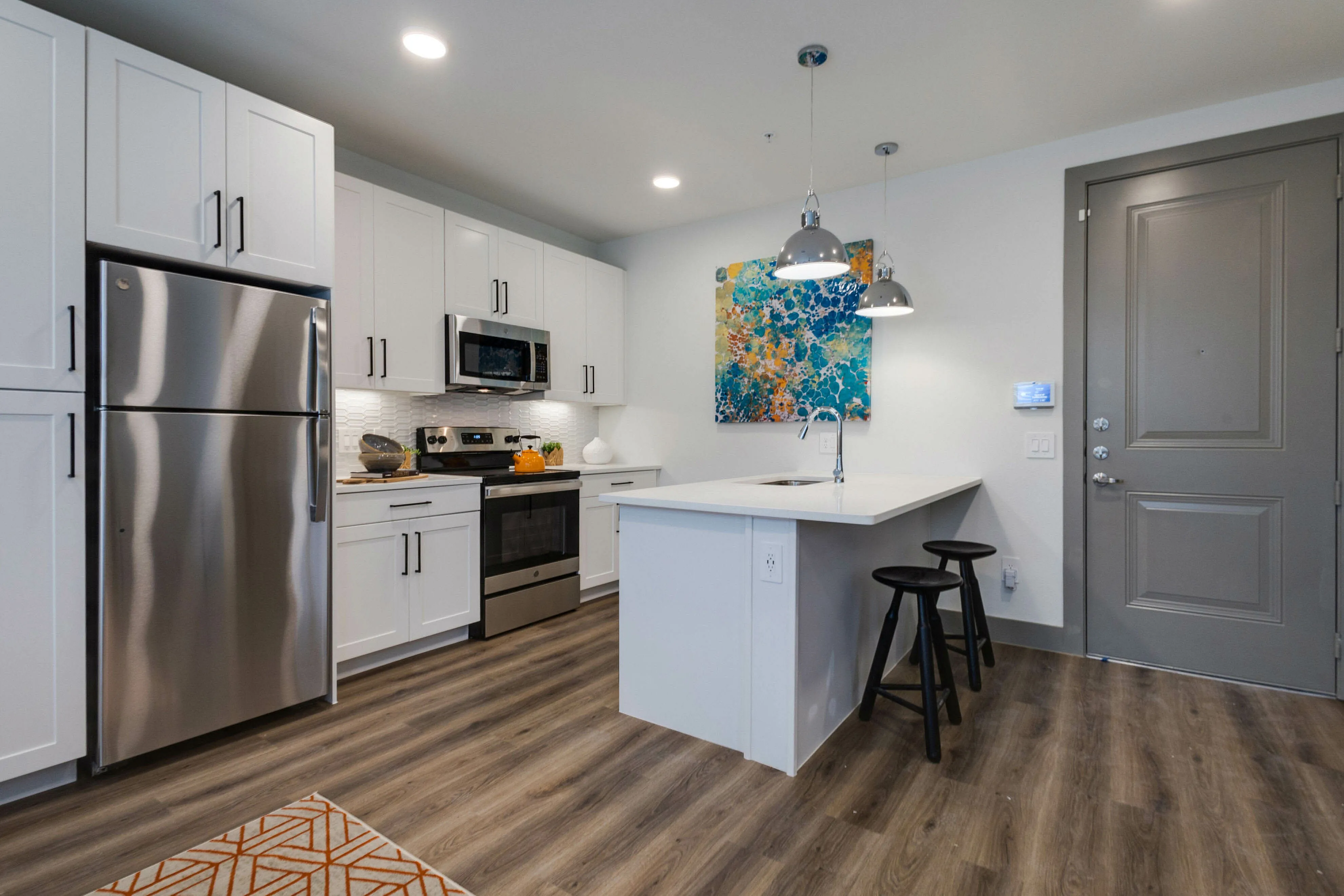 Decorated modern kitchen with stainless stee appliances, white cabinetry, and breakfast bar