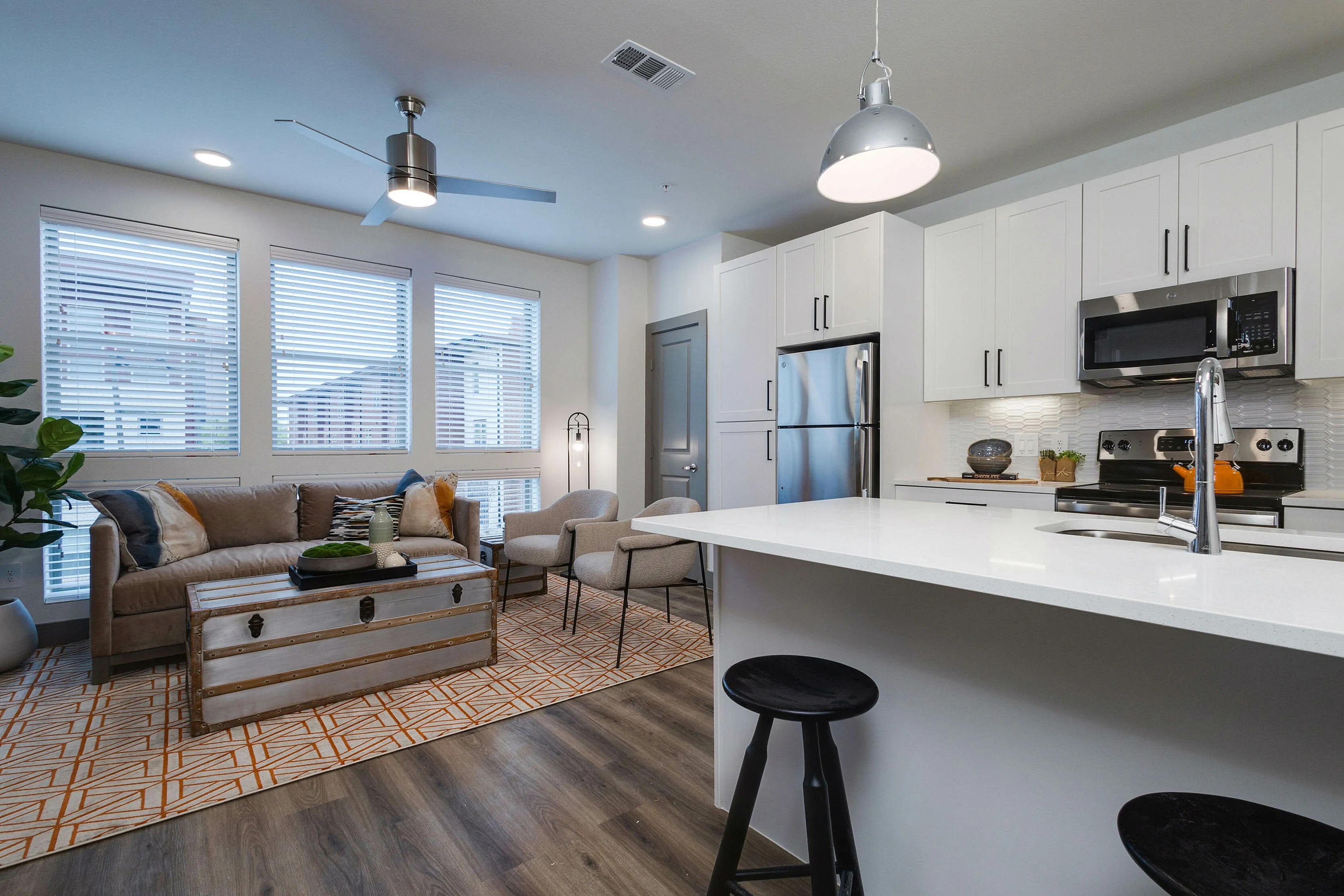 Kitchen, breakfast bar, leading into living area with large windows.