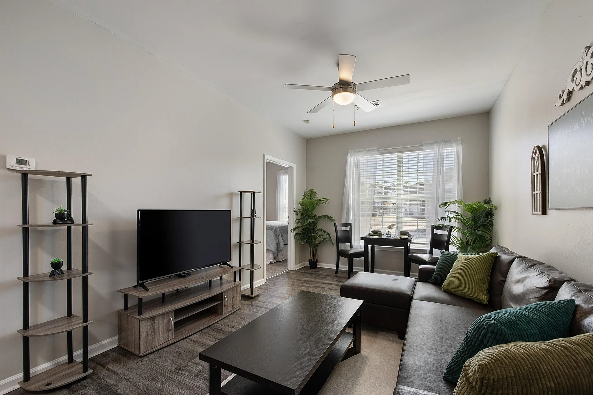 Model living room with black couch and tv