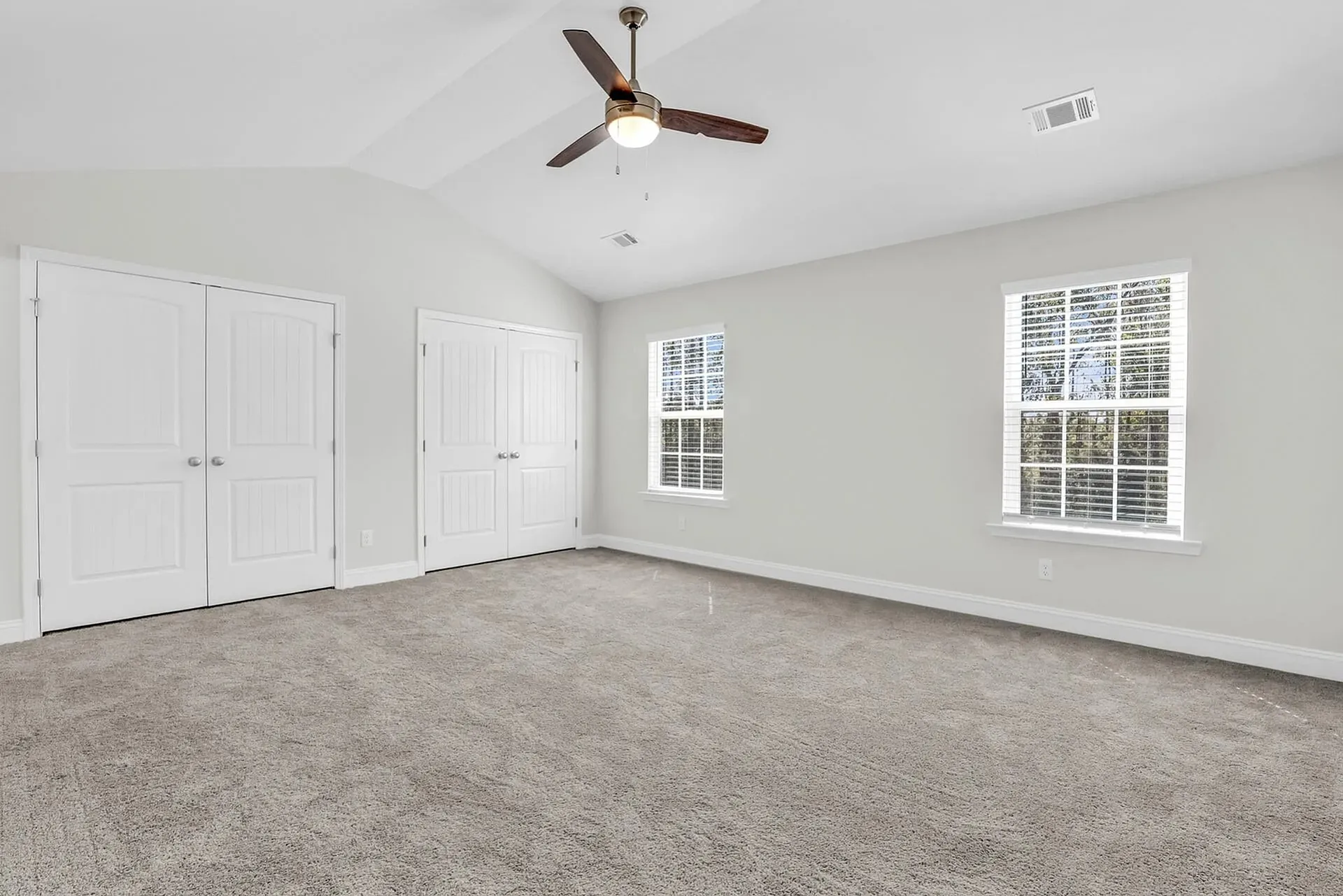 Statesboro, GA, Townhomes Near Georgia Southern University - The Outpost - Spacious Bedroom With Carpeted Flooring, Vaulted Ceiling, Ceiling Fan, Double Closets, And Wide Windows.