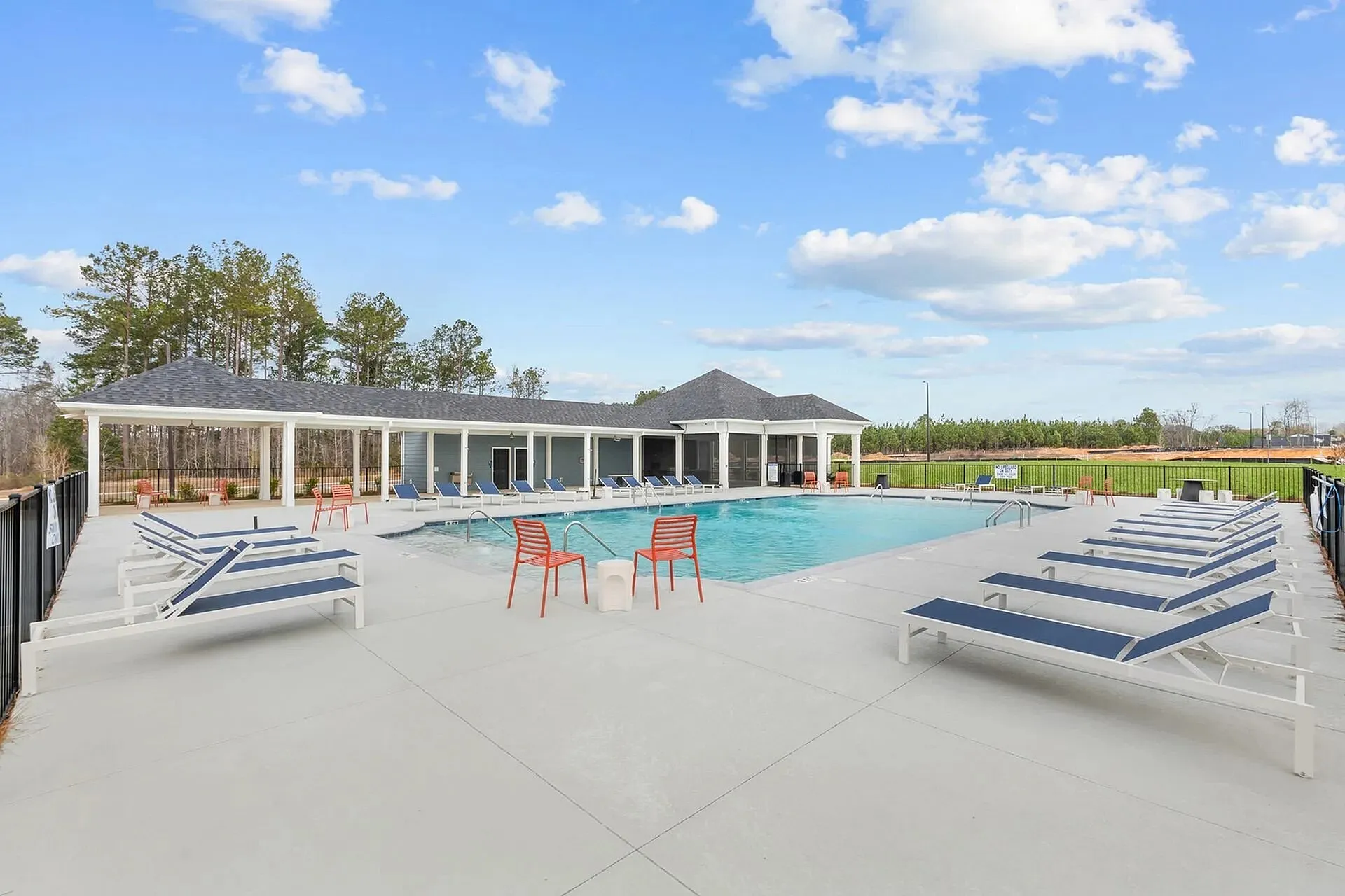 Statesboro, GA, Pet-Friendly townhomes - The Outpost - Resort-Style Pool With Lounge Chairs, Spacious Sundeck, Covered Patio Seating, And Open Sky.