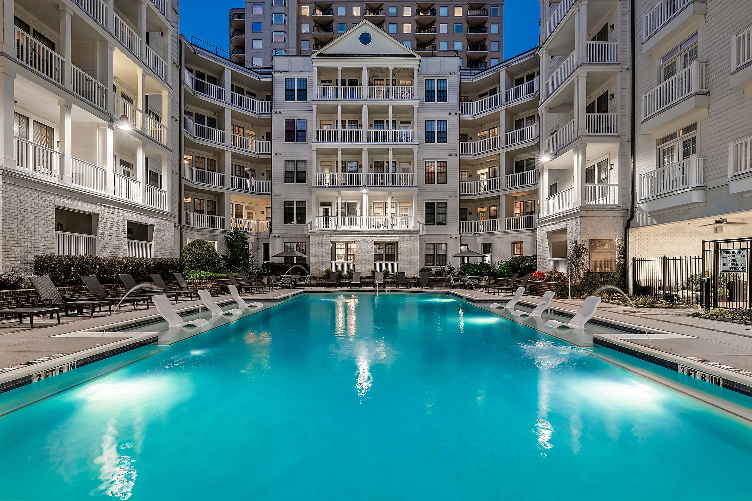 Swimming pool with sundeck and lounge chairs at dusk