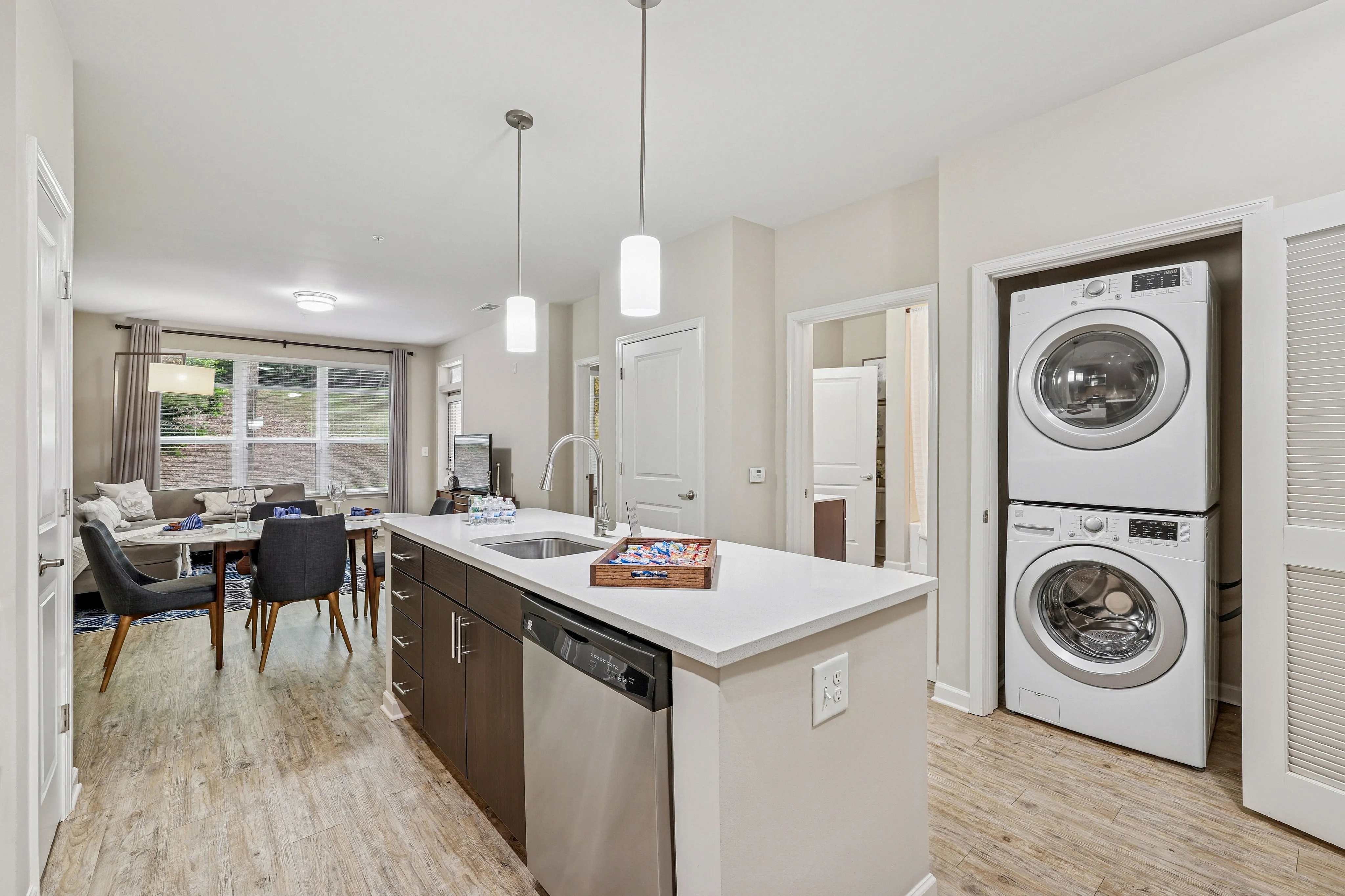 Kitchen island with brown cabinetry and stackable washer and dryer
