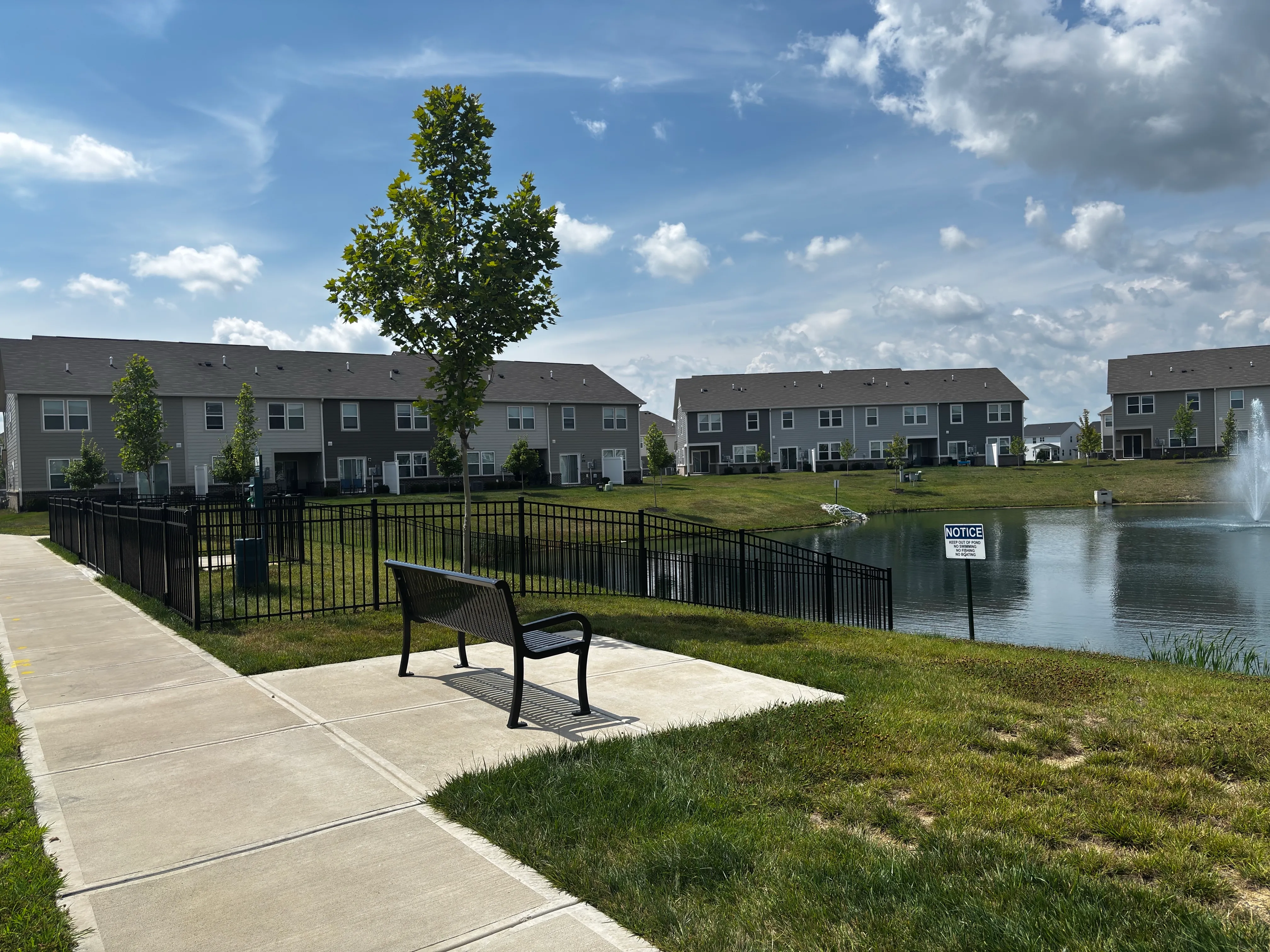 Picturesque community with modern townhouses, serene pond, and scenic walkway for a tranquil lifestyle.