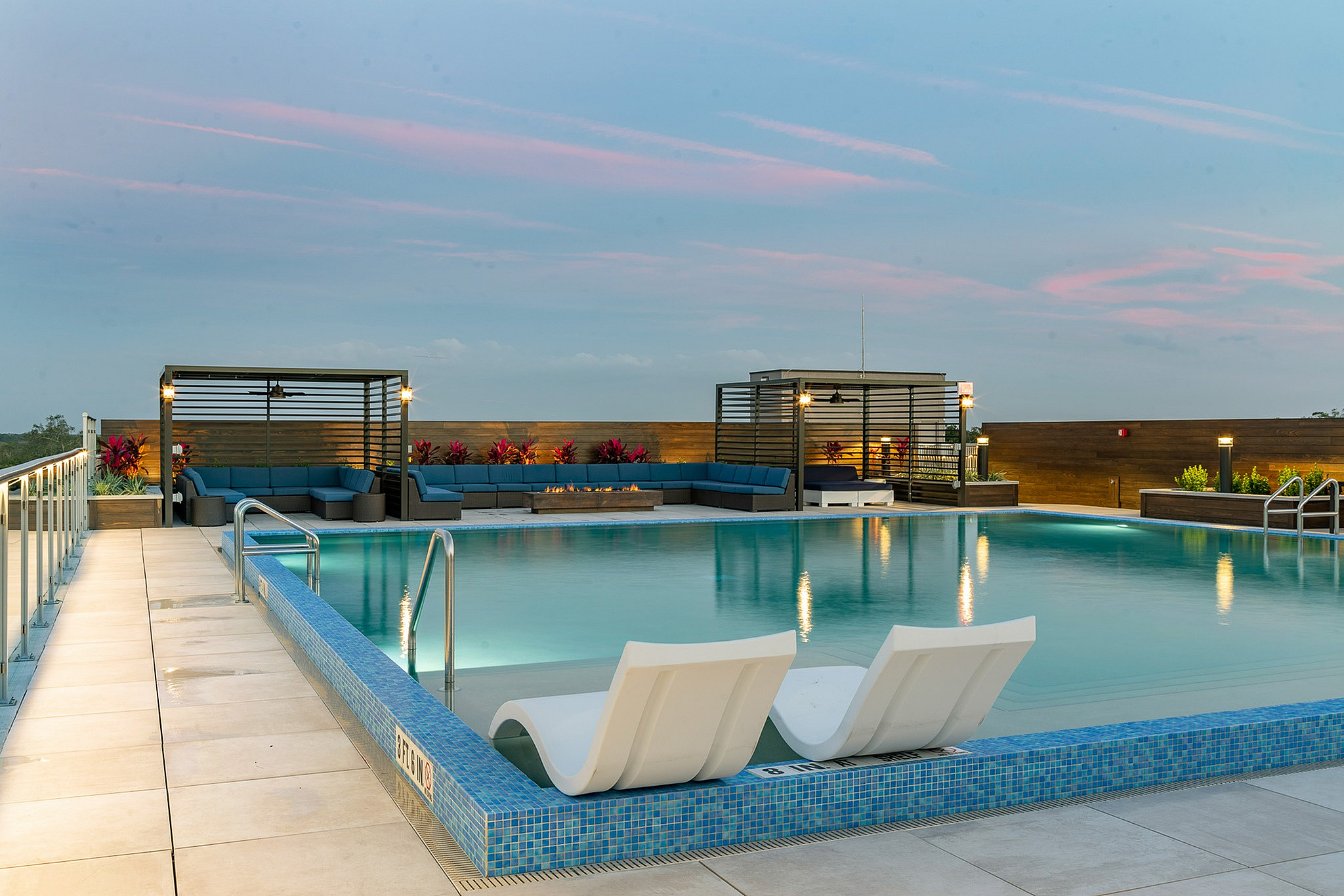Luxurious rooftop pool with stylish lounge areas and stunning sunset sky views.