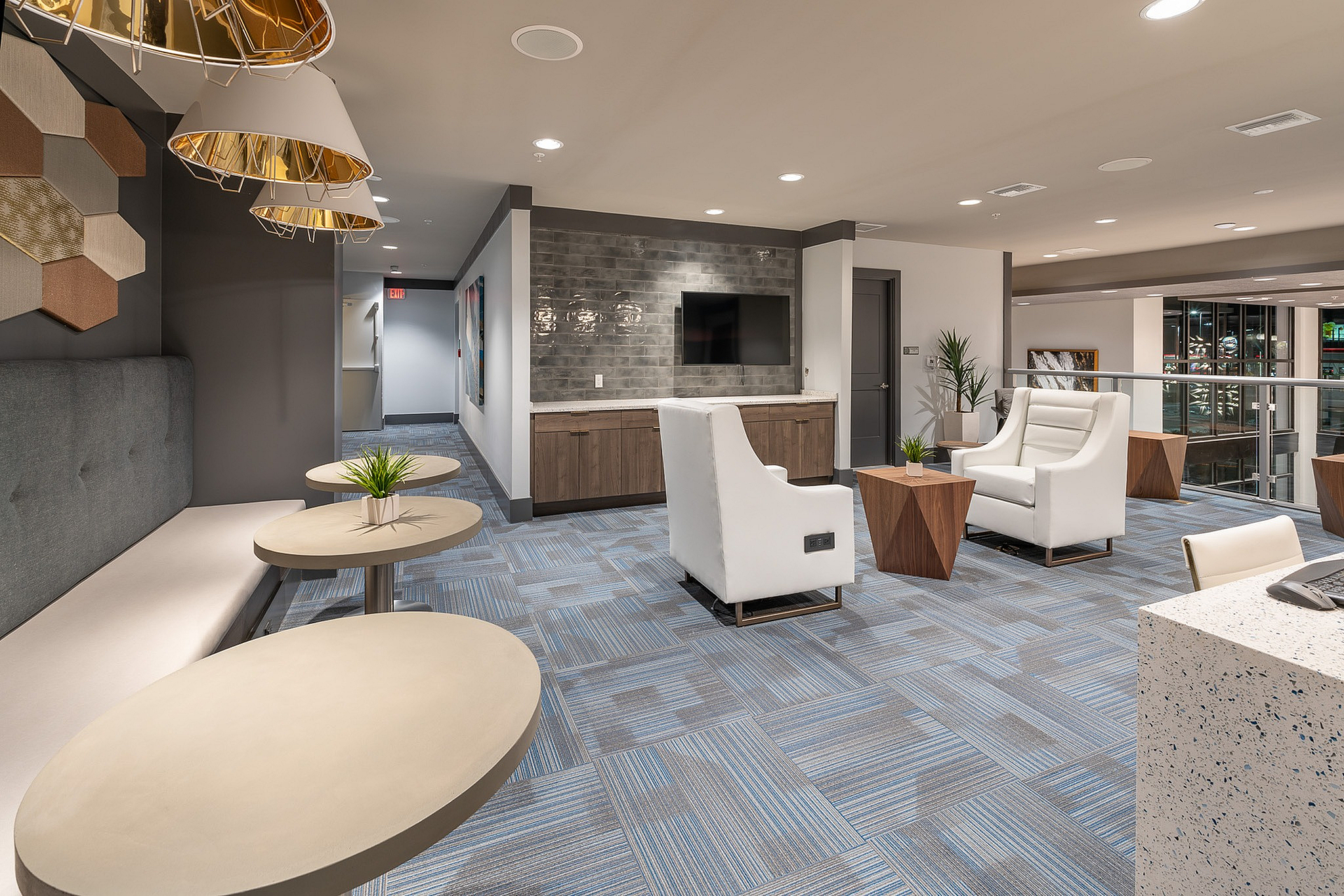 Modern apartment lounge area with sleek seating, stylish geometric tables, and contemporary lighting creating a welcoming ambiance.