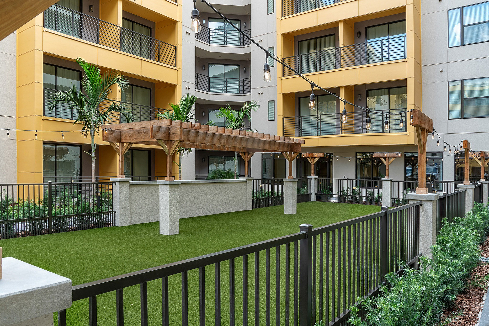 Charming apartment courtyard with lush greenery, stylish pergolas, and modern balconies, perfect for relaxing outdoor gatherings.