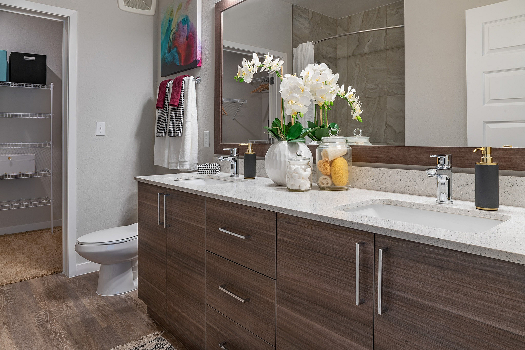 Elegant bathroom with a modern double vanity, stylish decor, and sleek wooden cabinets, offering a touch of luxury and comfort.