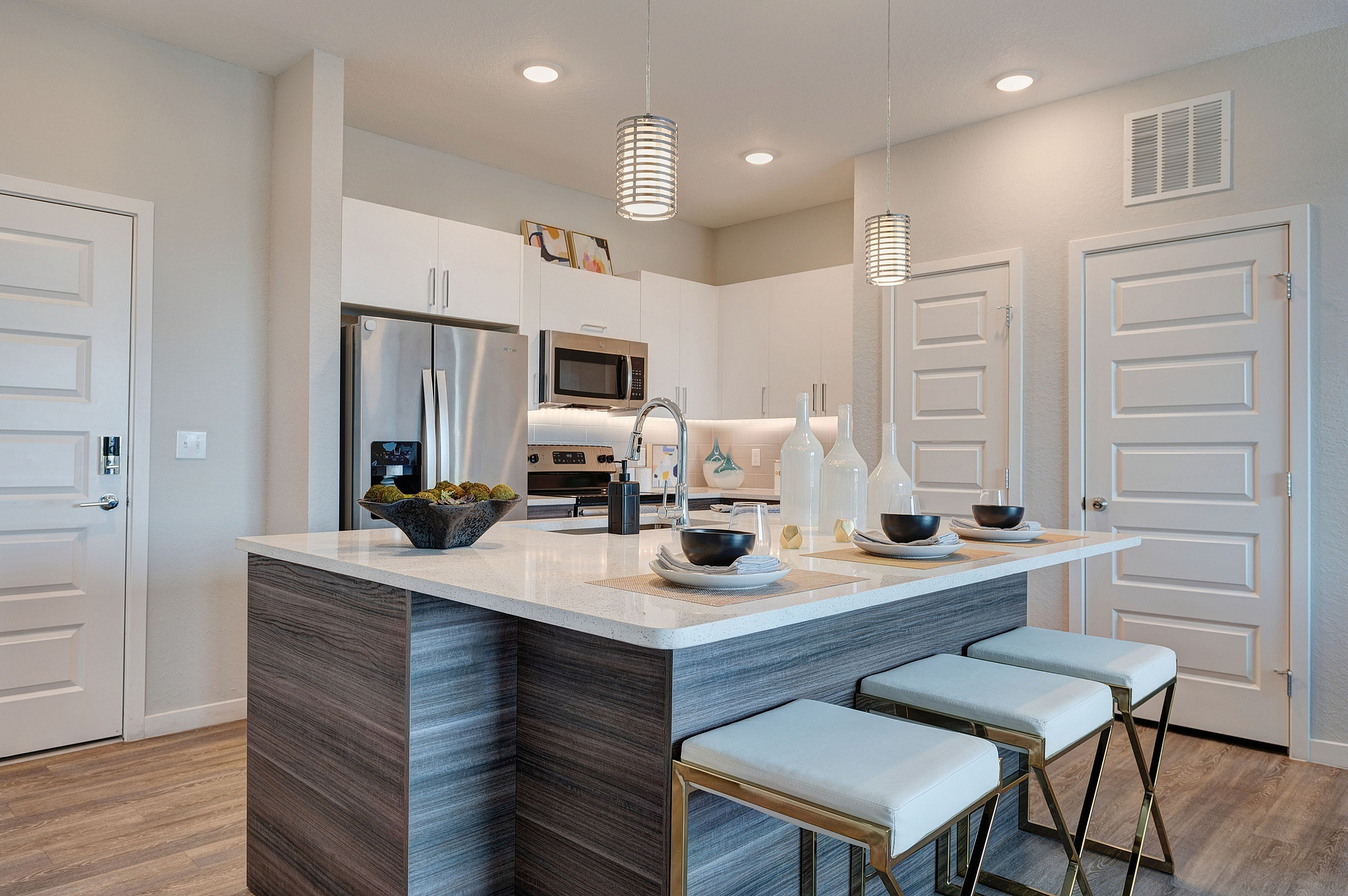 Modern kitchen with sleek stainless steel appliances, elegant pendant lighting, and a chic breakfast bar with stylish seating.