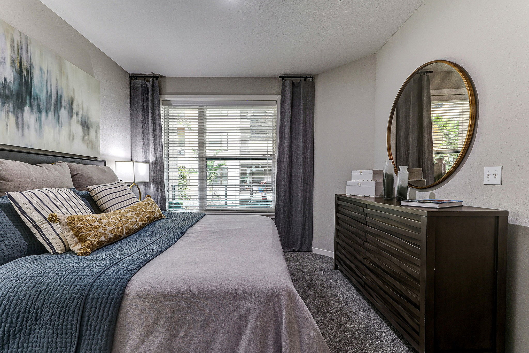 Chic bedroom with a cozy bed, modern artwork, and large windows offering natural light.