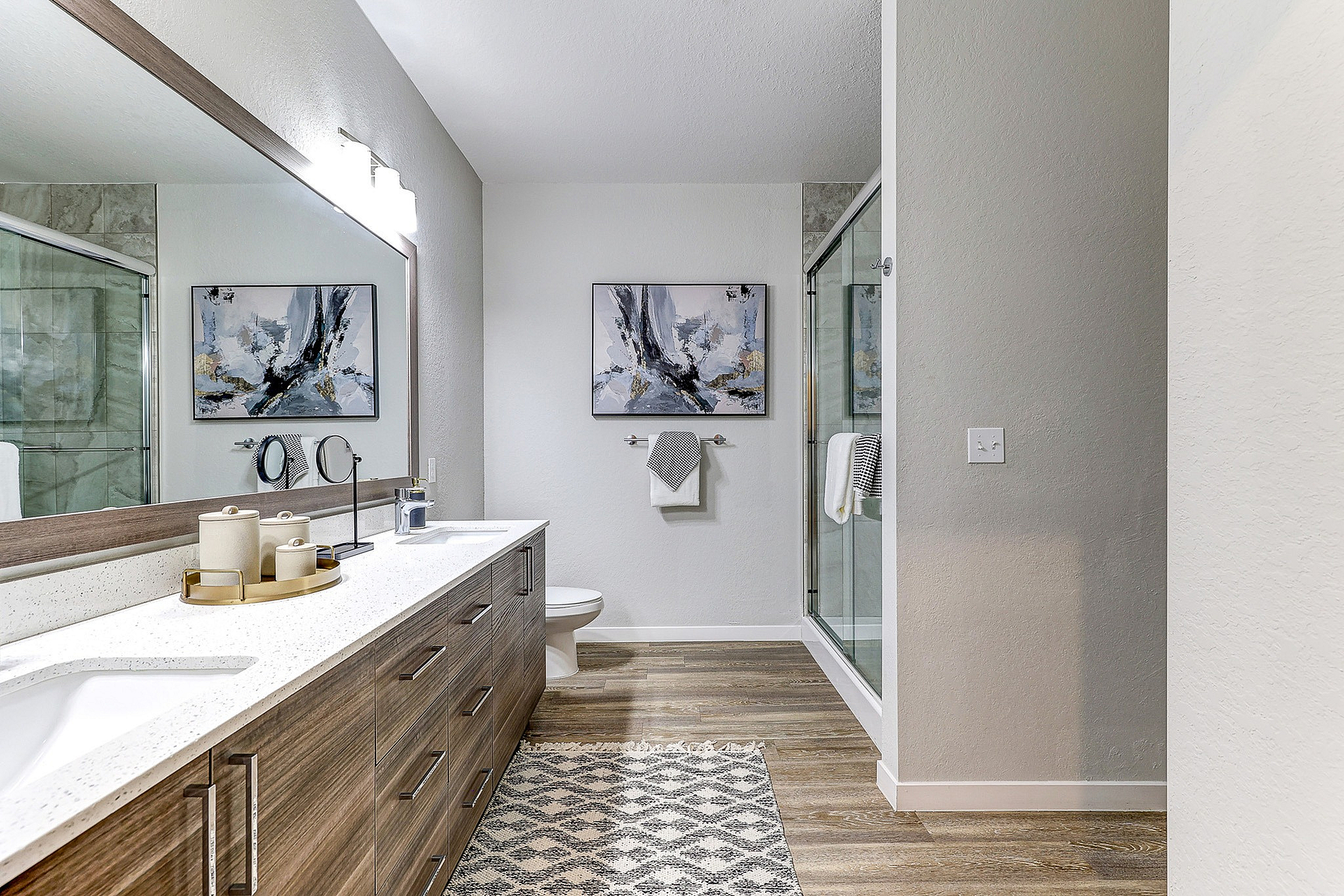 Elegant modern bathroom with a sleek double vanity, large mirror, and spacious glass shower.