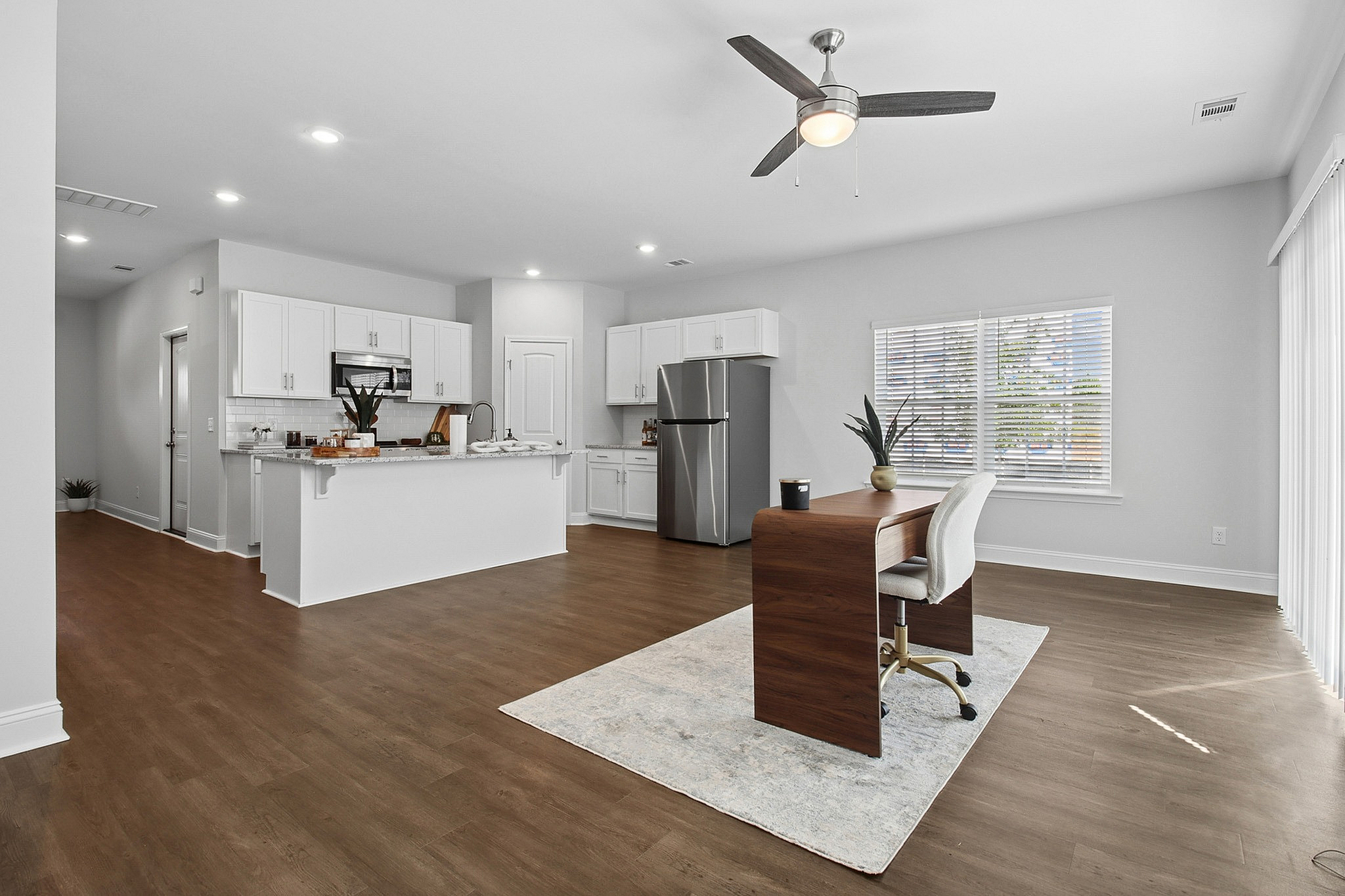 Bright open-concept kitchen and living area featuring modern stainless steel appliances, elegant wood flooring, and abundant natural light.