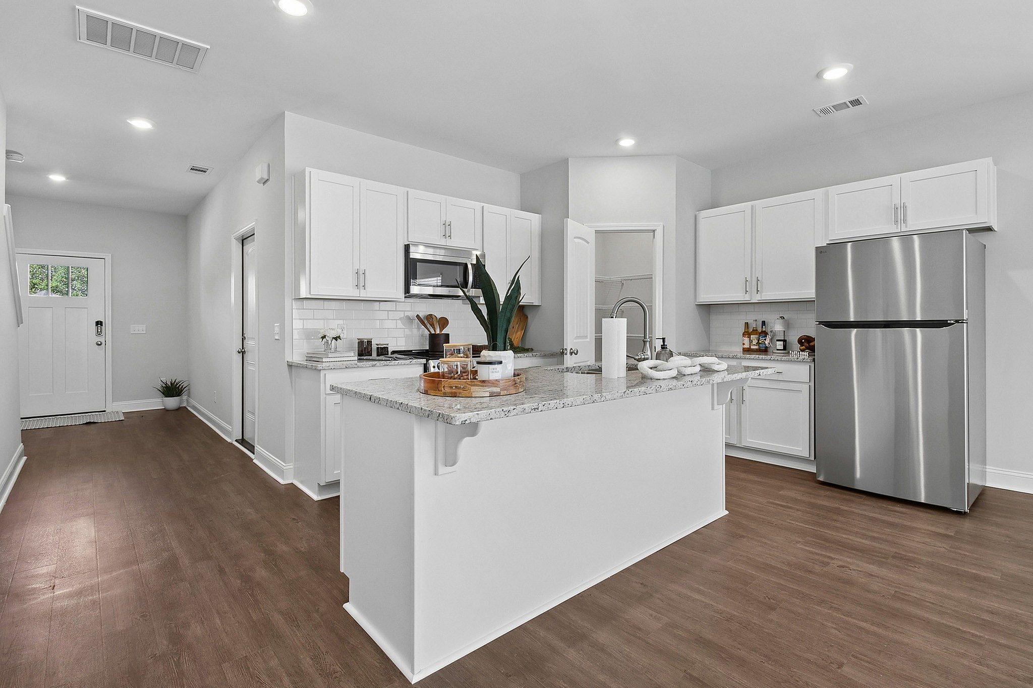 Bright, modern kitchen with sleek white cabinetry, granite countertops, and stainless steel appliances, featuring an inviting open layout design.