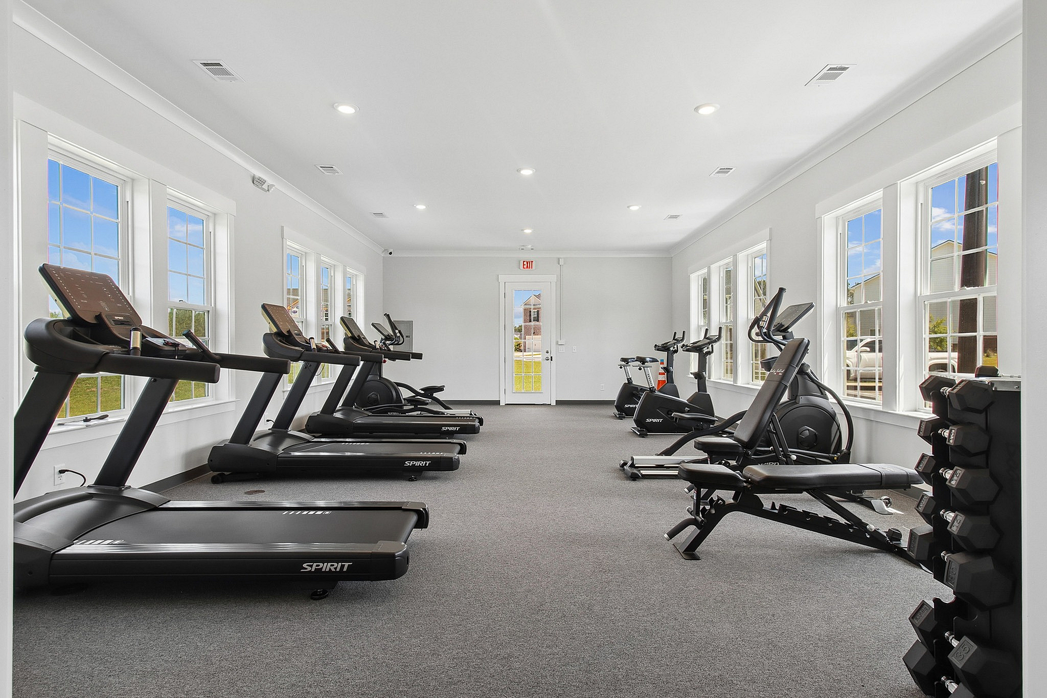 Modern fitness center with state-of-the-art treadmills and exercise bikes, abundant natural light, and sleek design.
