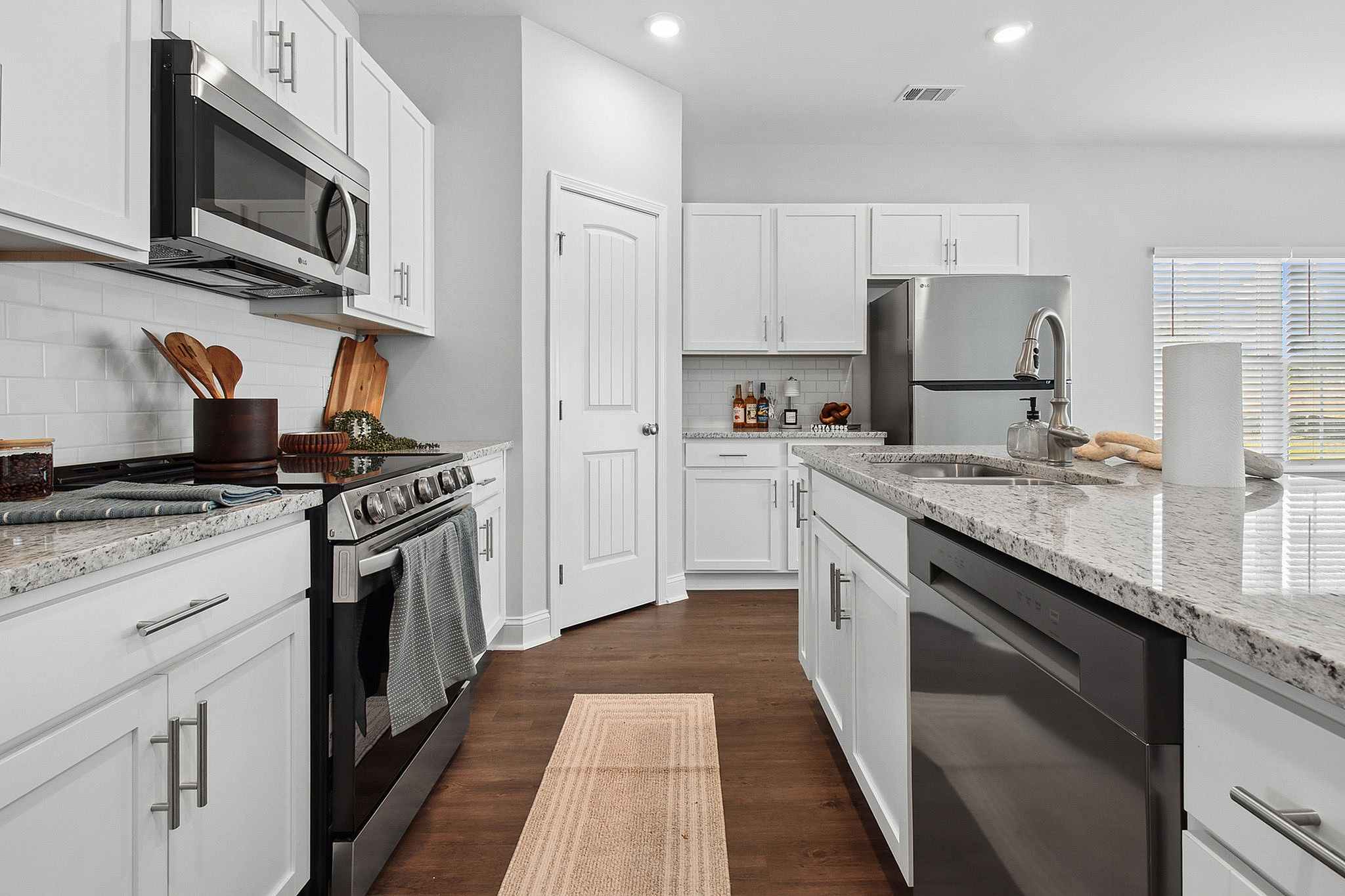 Modern kitchen featuring sleek stainless steel appliances, elegant white cabinetry, and a stylish granite countertop island.