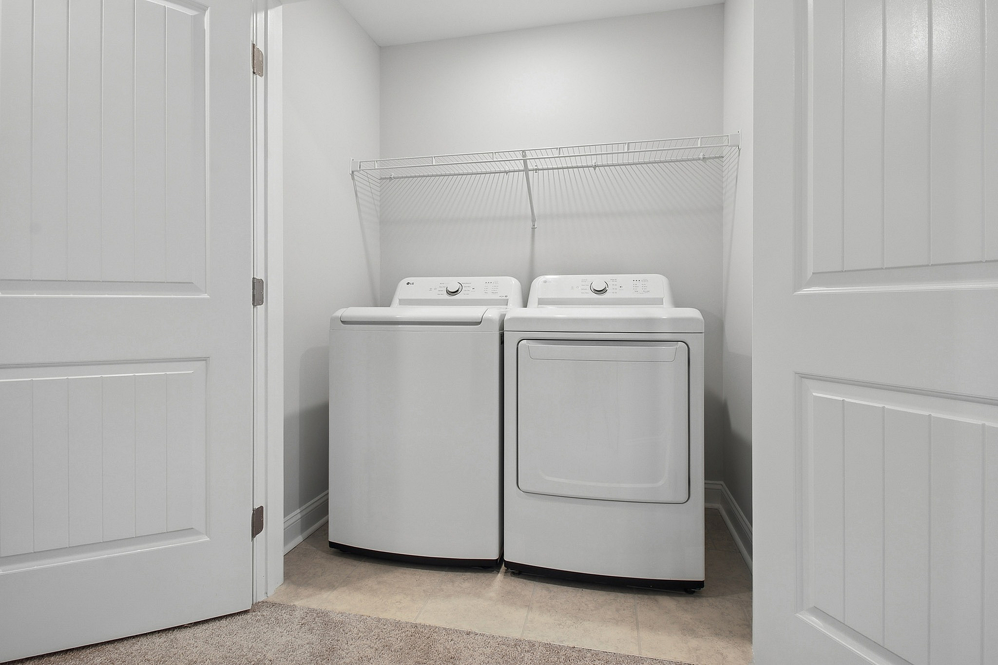 Bright and functional laundry area featuring modern washer and dryer with ample storage shelf.