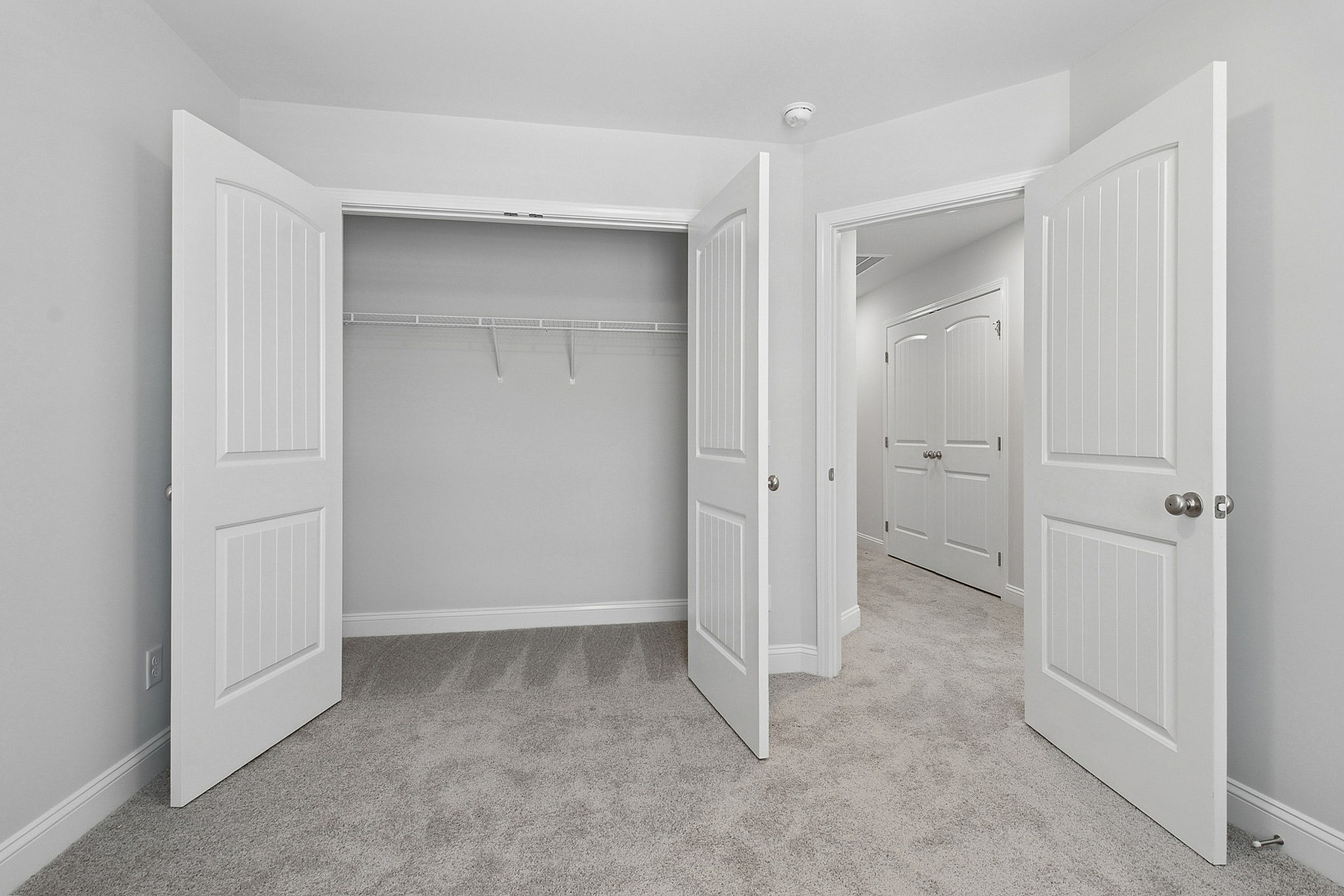 Modern apartment showcasing a spacious walk-in closet with elegant double doors and plush carpeting.