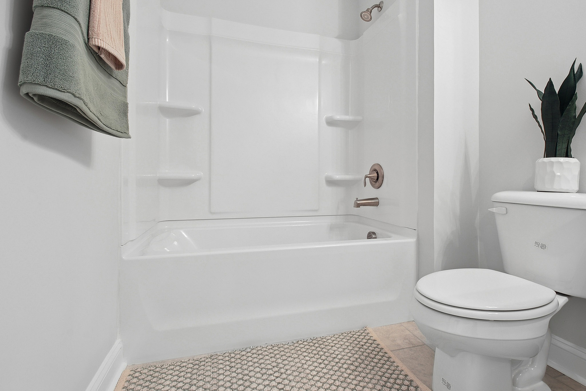 Modern bathroom featuring a pristine white bathtub, elegant fixtures, and a stylish plant accent, creating a sleek and inviting space.