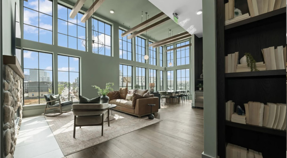 Spacious and sunlit loft living room with floor-to-ceiling windows and elegant furnishings.