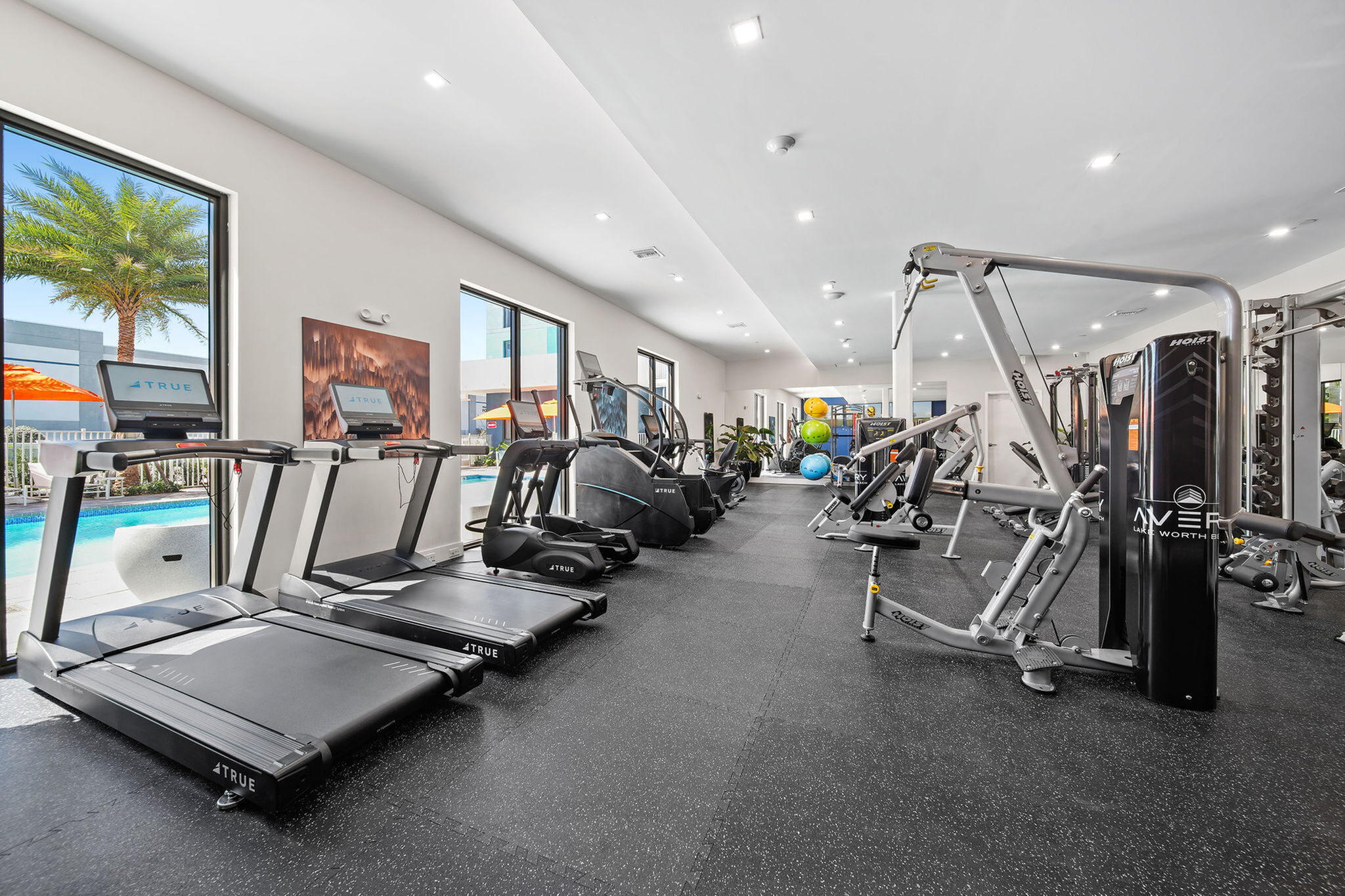Modern fitness center with state-of-the-art equipment, overlooking a refreshing outdoor pool through large windows.