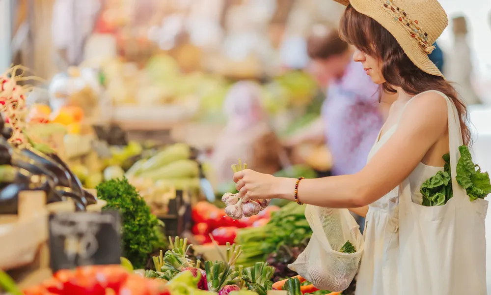 woman picking up garlic at farmers market