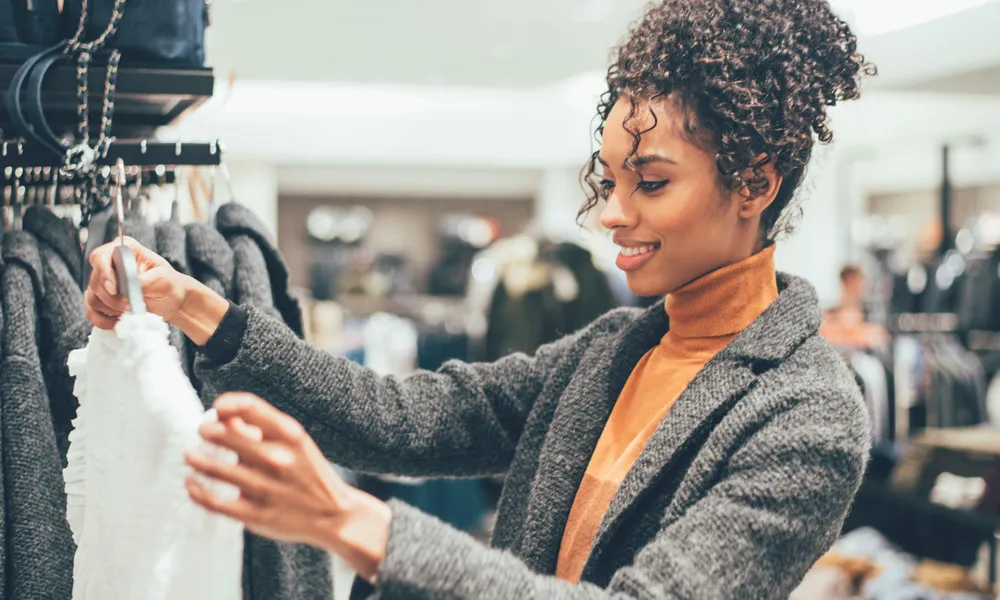 woman holding up blouse in clothing store
