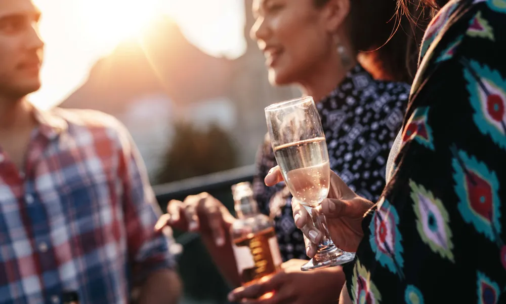 three people standing with drinks in hand