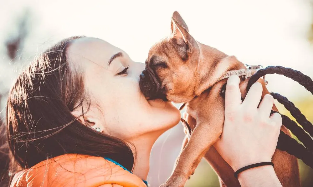 woman kissing dog outside