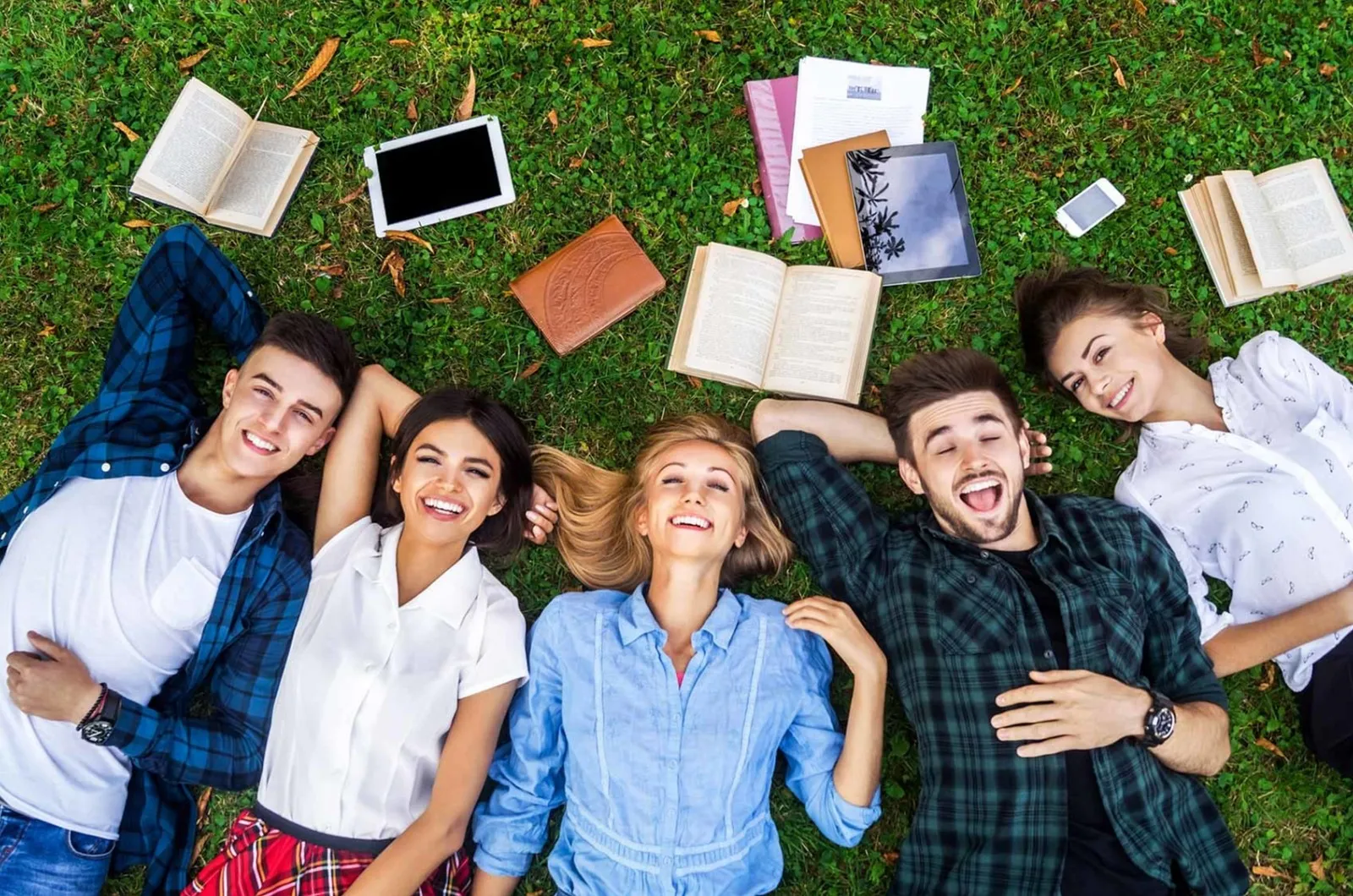students laying on grass with books