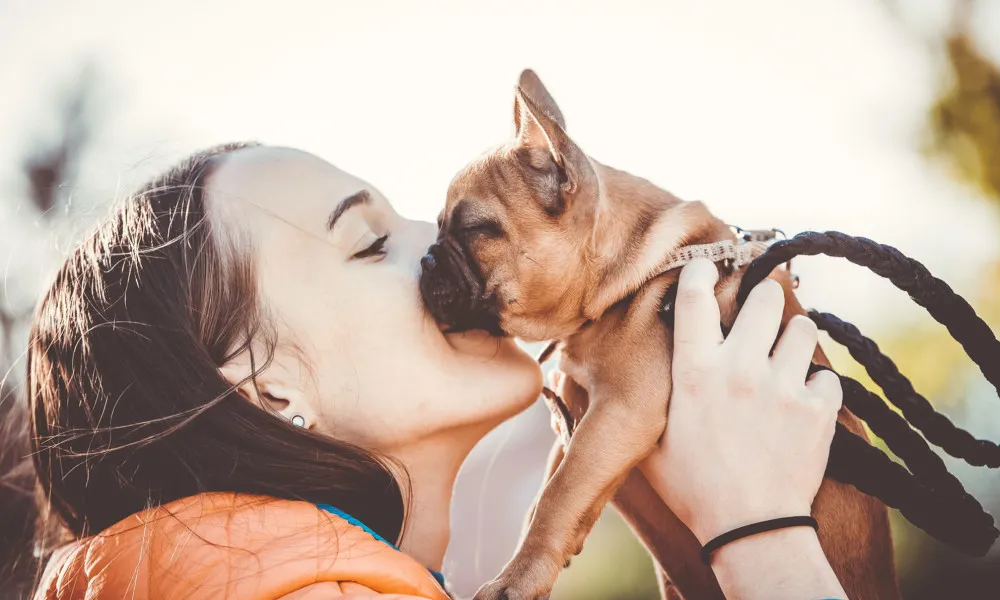 woman kissing dog outside