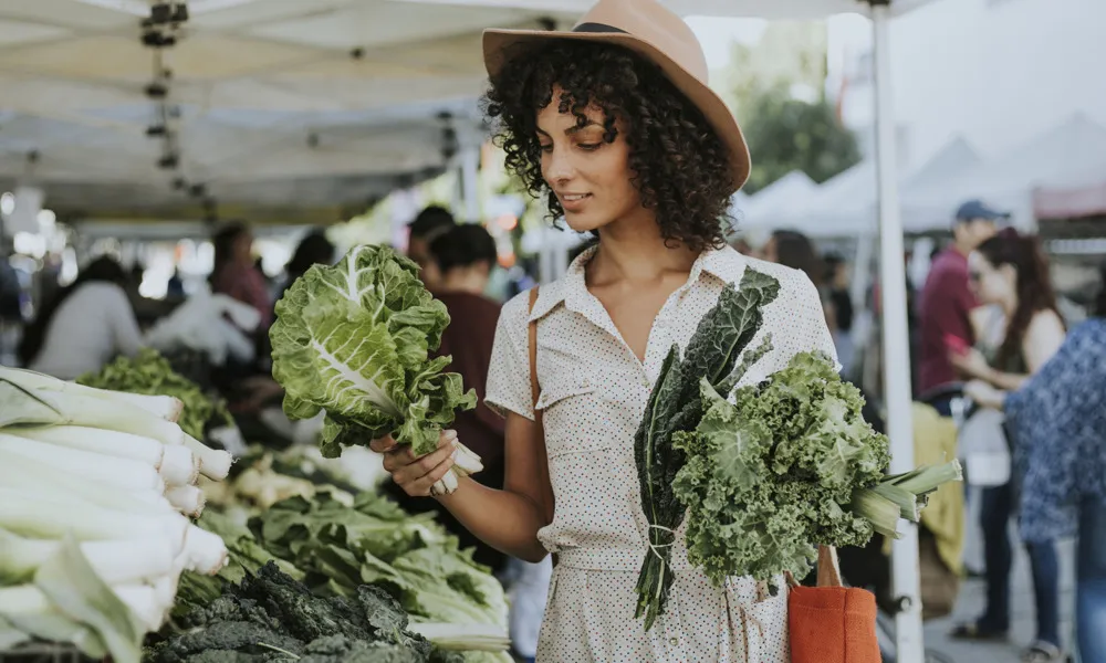 woman with vegetables in hand at outdoor farmers market in daytime