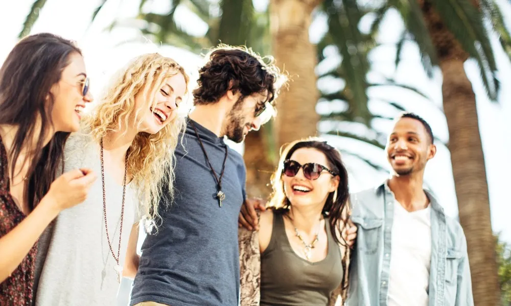 group of friends walking on the beach with palm tree in back ground