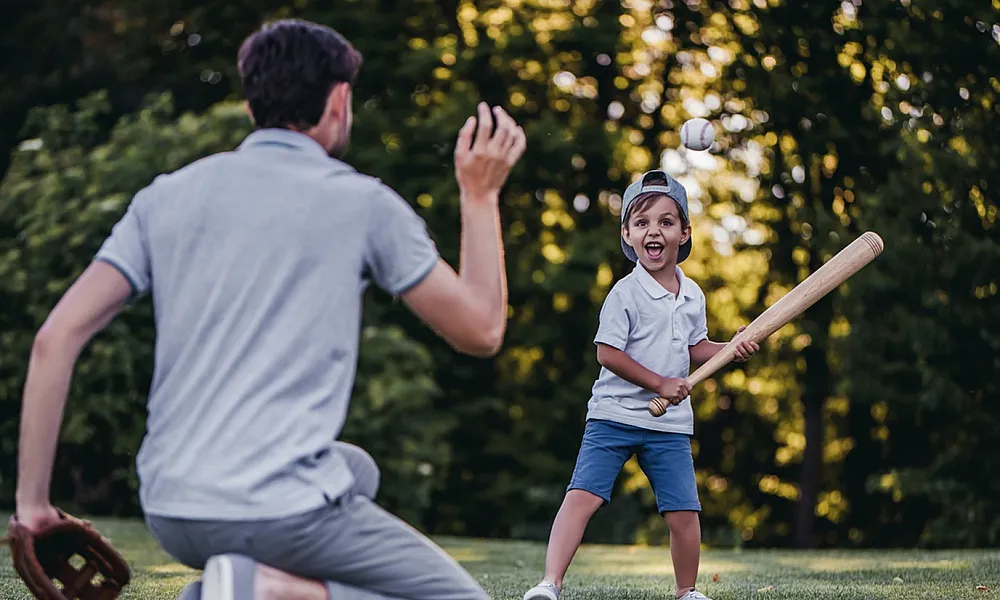 Dad playing ball with son in a park