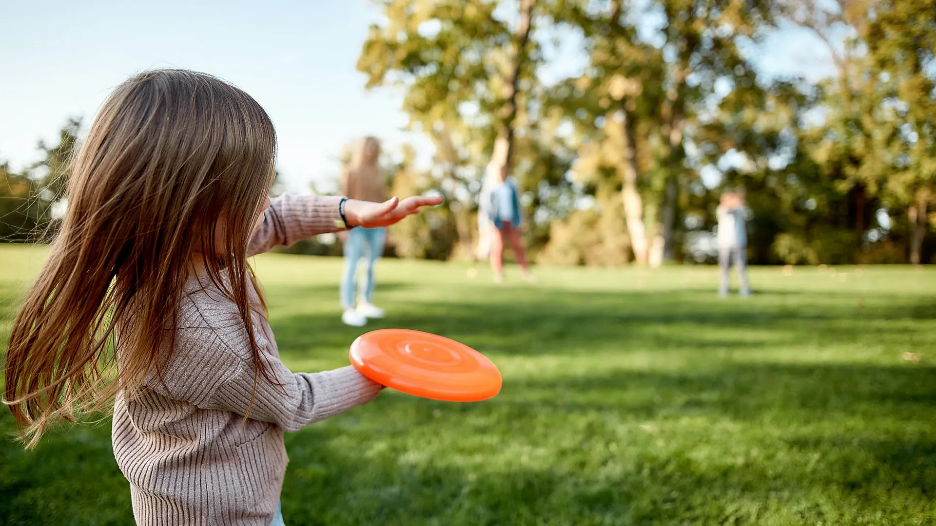little girl throwing a frisbee in the park