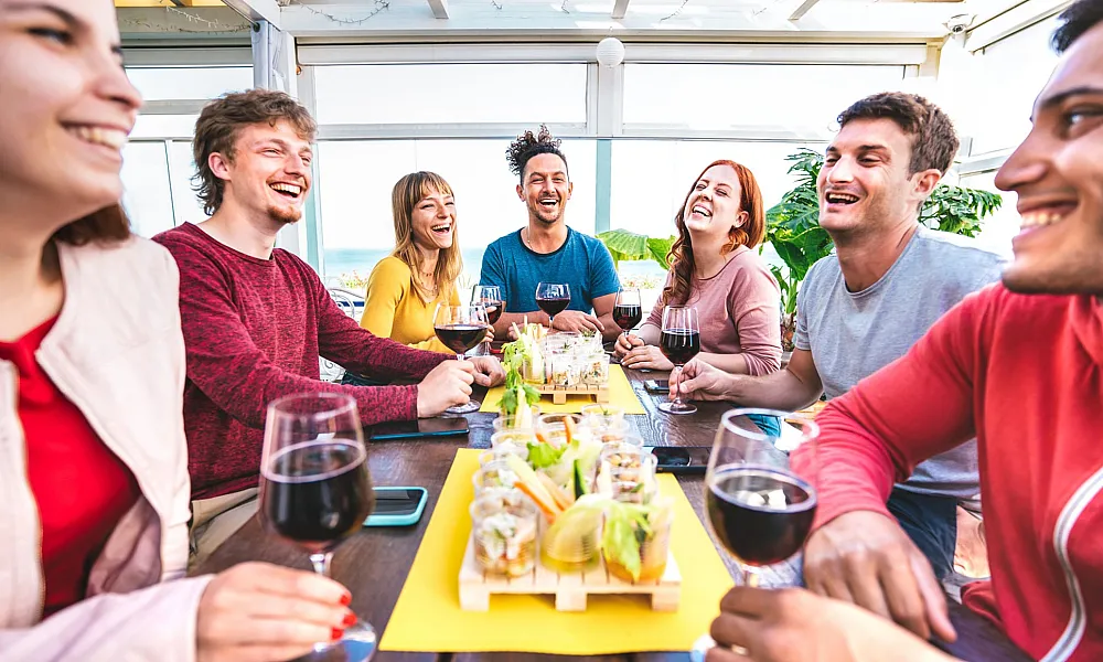 group of friends smiling and eating together on a restaurant patio