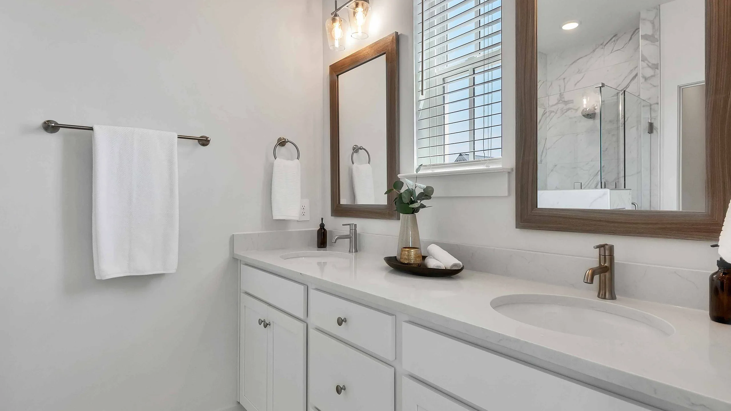Elegant modern bathroom with dual sinks, sleek marble countertops, and stylish mirrors, offering a serene and luxurious atmosphere.