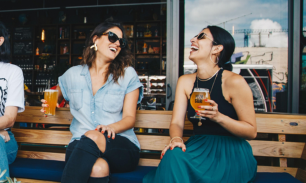 Two women laughing over beer
