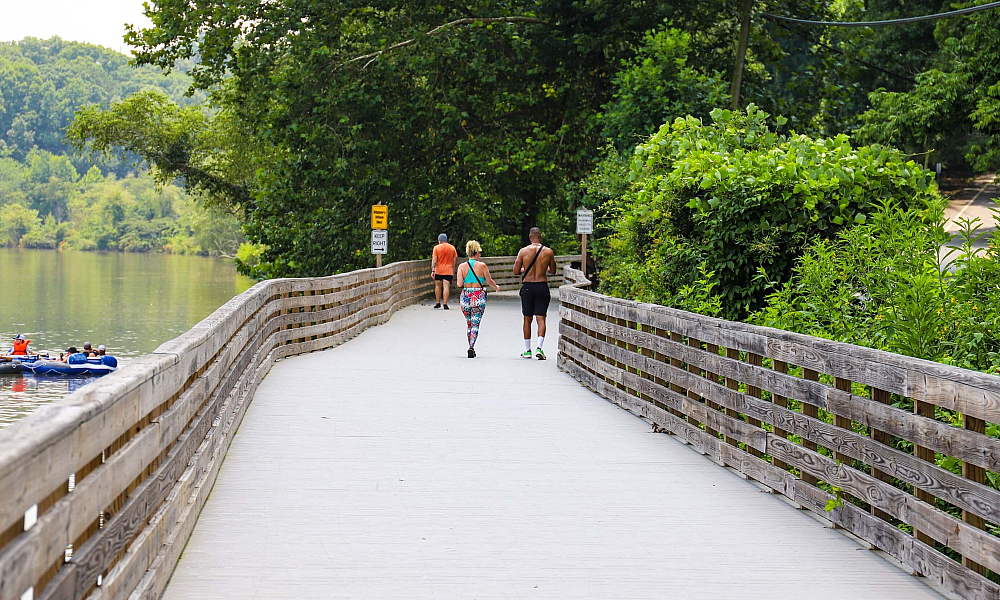 people walking along dock next to river