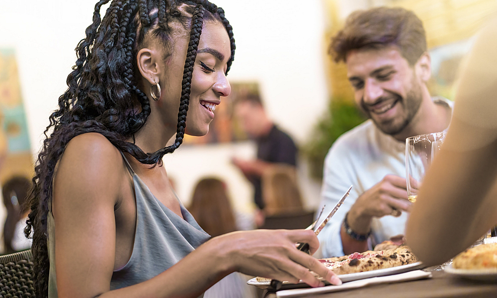 woman eating pizza outdoors with friends