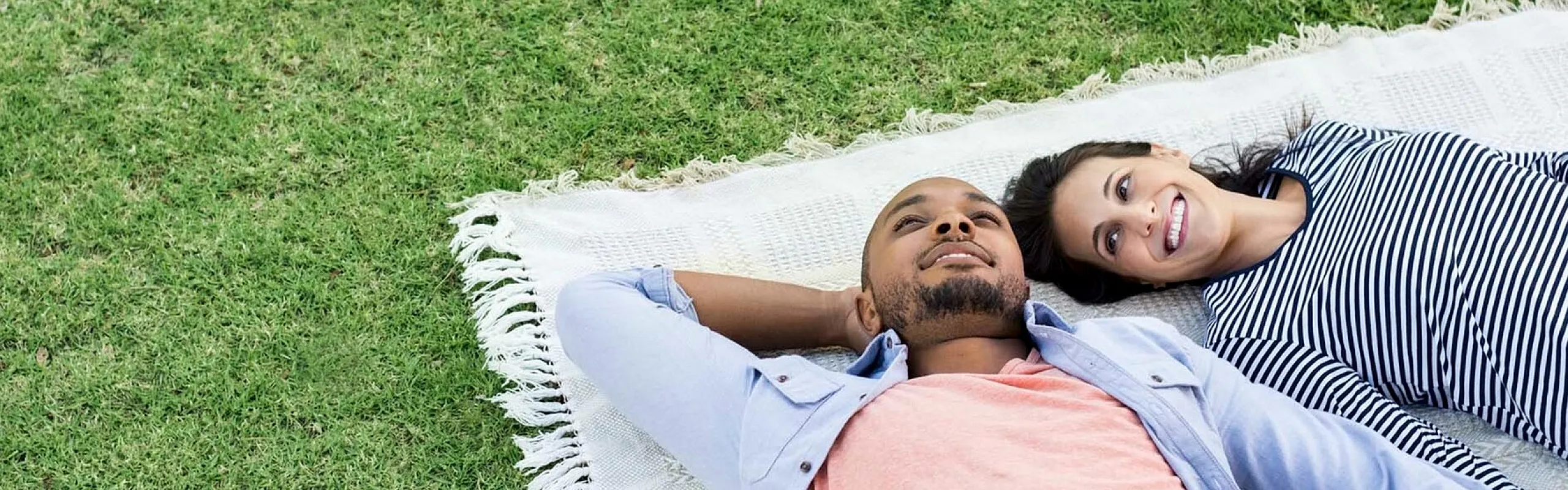 couple laying on a blanket in a park