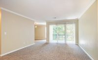 Bright and inviting living space with large windows, plush carpet, and open access to the outdoors, perfect for relaxation and entertaining.