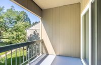 Bright balcony with wooden railing, overlooking lush greenery, perfect for peaceful relaxation.