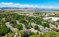 Beautiful aerial view of a serene residential area surrounded by lush greenery and distant mountains under a clear blue sky.